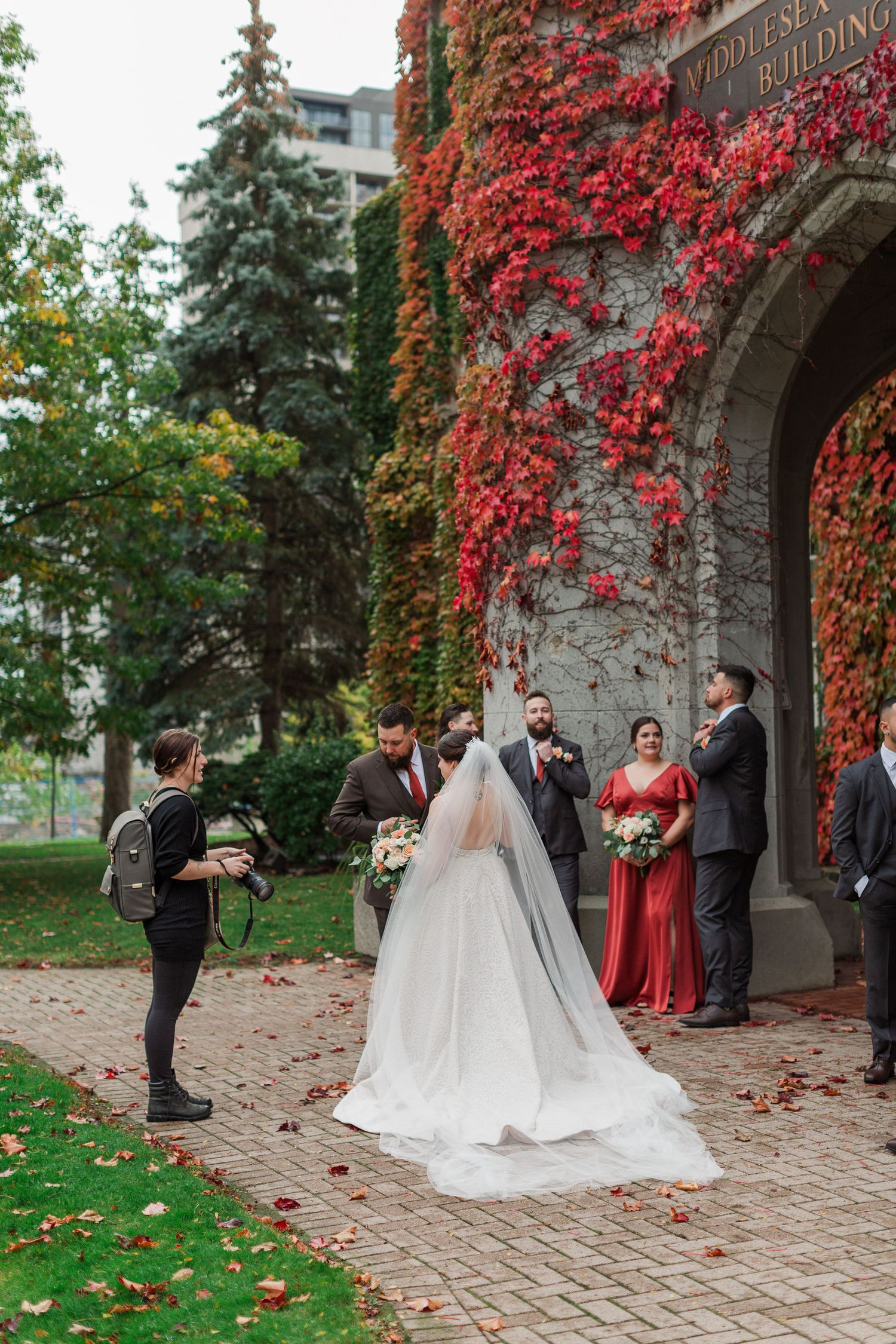 The Photographer, Jacquie, giving instructions to the bride and groom and their wedding party at the old courthouse near woodstock, ontario.