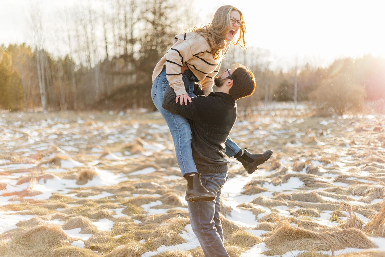 Candid sunset winter engagement photo of couple in a field laughing together at the guelph arboretum in guelph, ontairo.