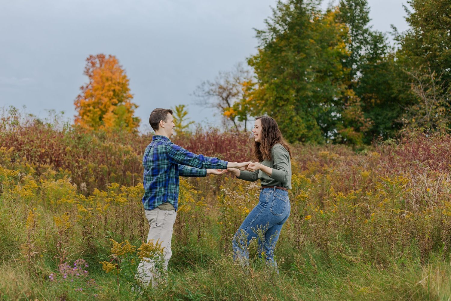 Candid engagement photo of couple spinning amongst the wild flowers in a field at the guelph lake conservation area.