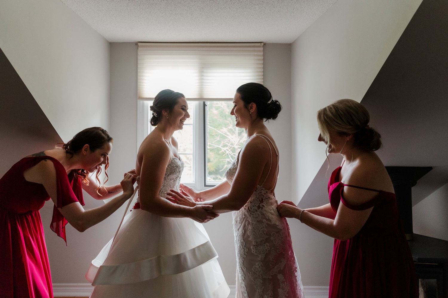 Two brides getting ready with their friends in front of the cottage bedroom winder at valley croft barn in Coldwater, On
