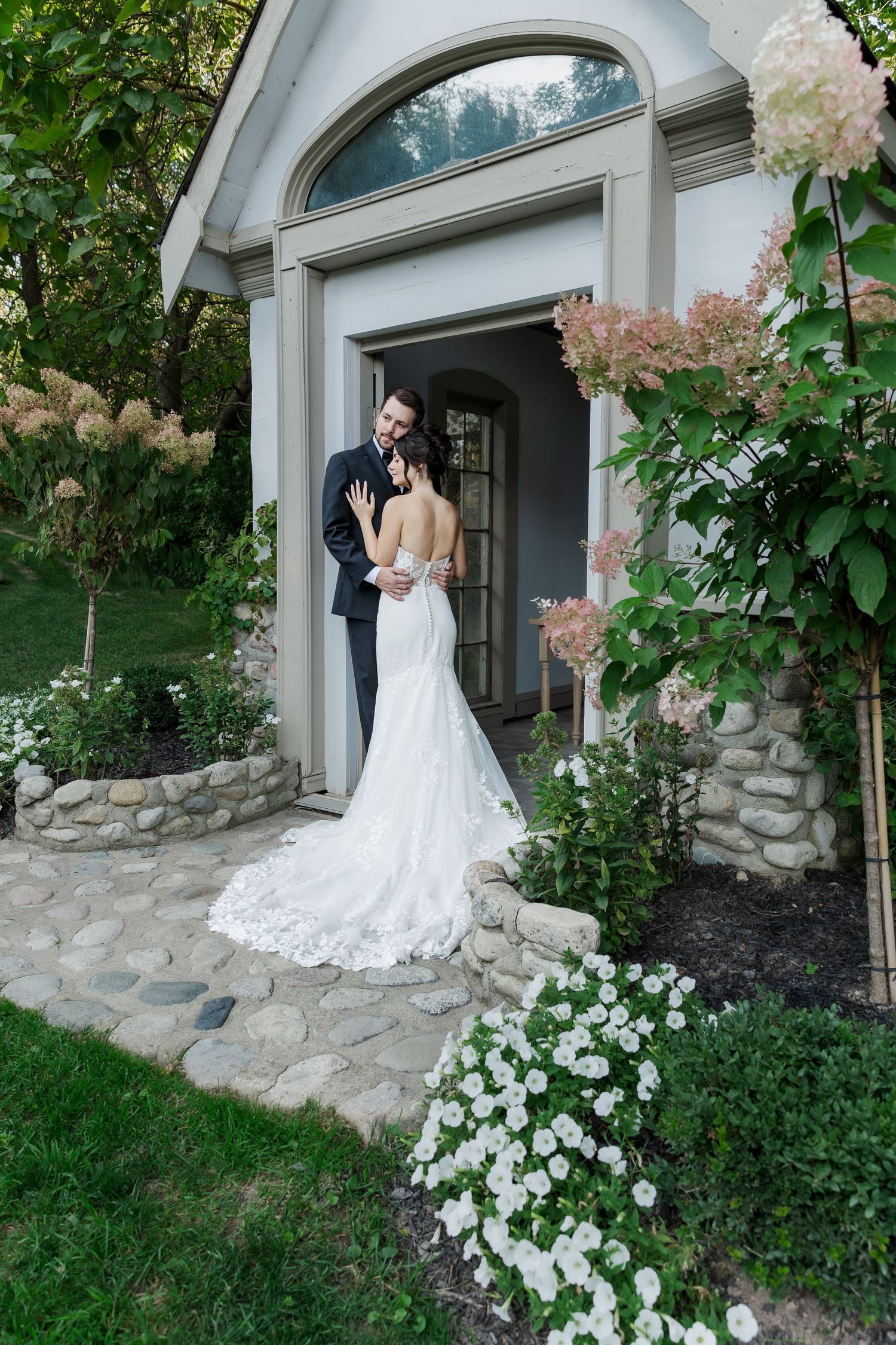 Relaxed wedding photography of bride and groom snuggle into each other in the doorway of a chapel at the Wren House in St. Jacobs, Ontario.