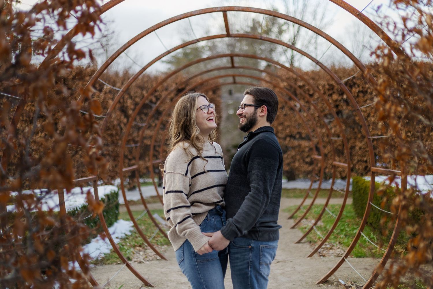 A couple shares an intimate moment surrounded by autumn foliage in a romantic outdoor setting.
