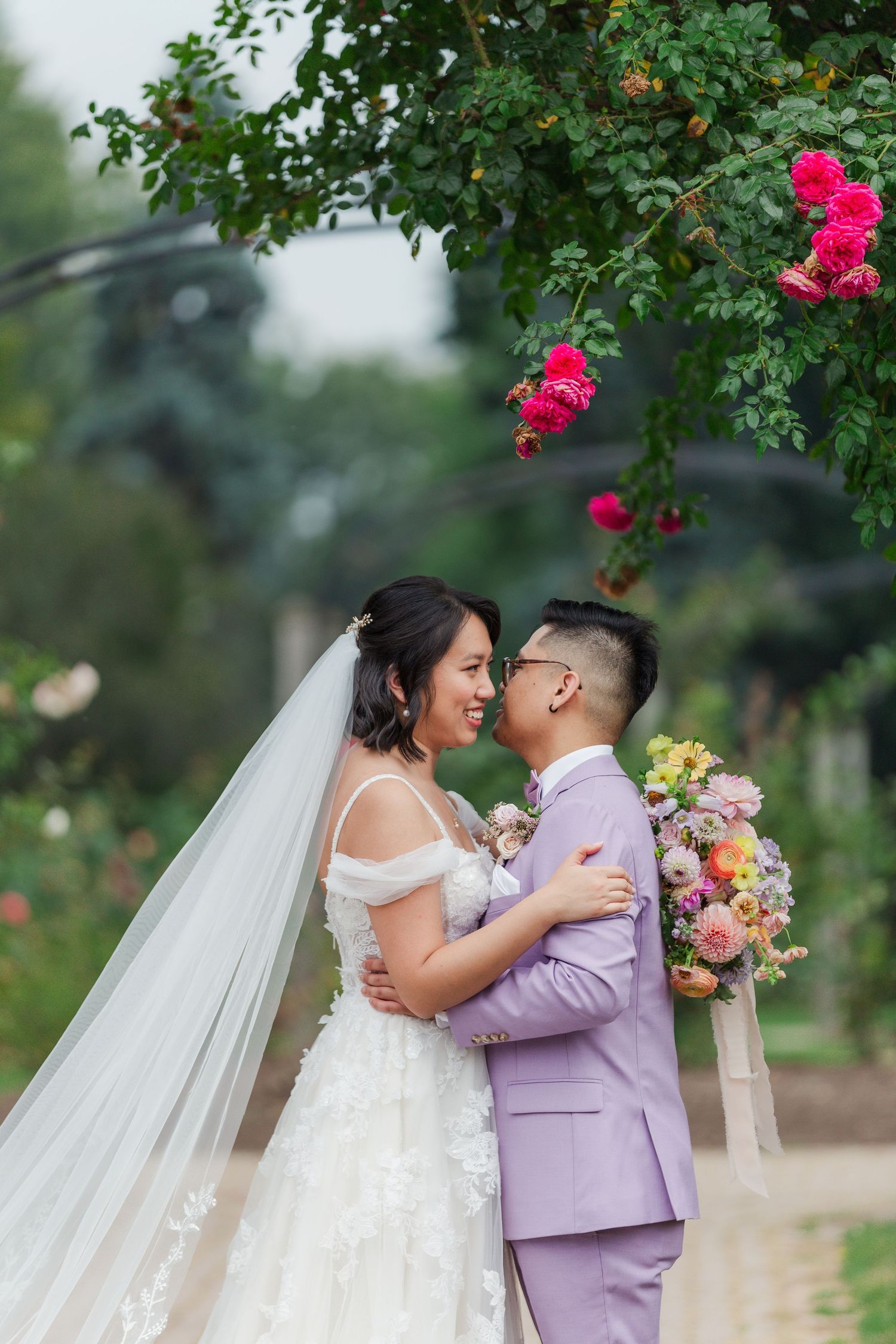 Natural wedding photo of bride and groom in a garden surrounded by roses in hamilton, ontario.
