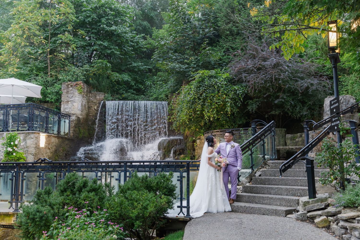 Calm wedding photo of bride and groom taking a moment while standing on the stairs beside the waterfall at the ancaster mill.