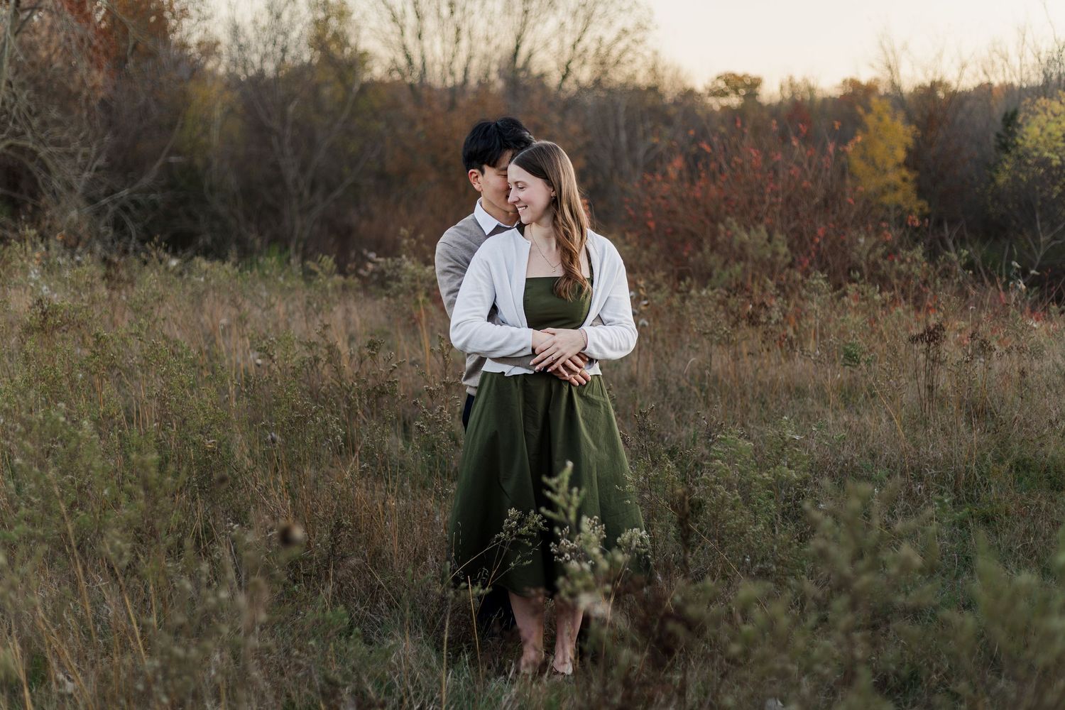 A couple embraces in a golden autumn field during sunset creating a romantic silhouette against the warm light.