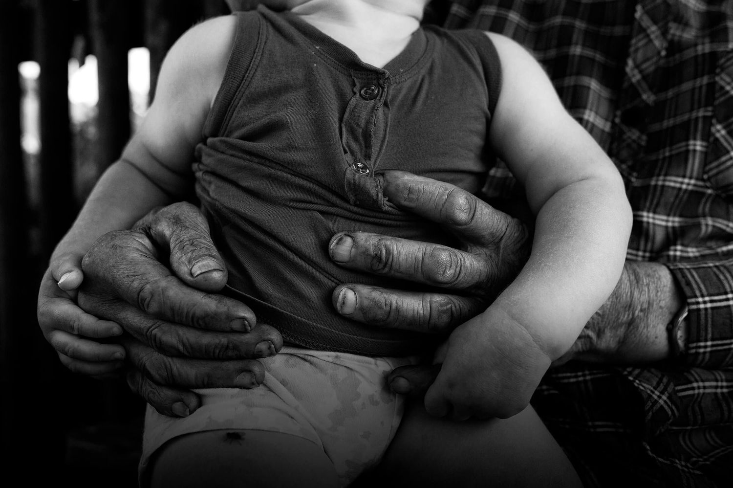 Fotografia przedstawiająca dłonie pradziadka obejmujące wnuka – symbol pokoleniowej bliskości i rodzinnych więzi autorstwa Anety Ludwig.