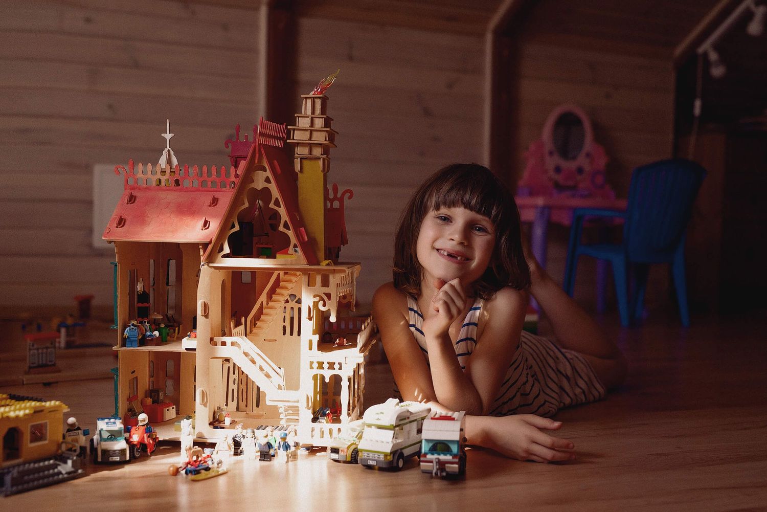 Uśmiechnięta dziewczynka bawiąca się domkiem i zabawkami LEGO – fotografia rodzinna w ciepłym świetle – Aneta Ludwig.