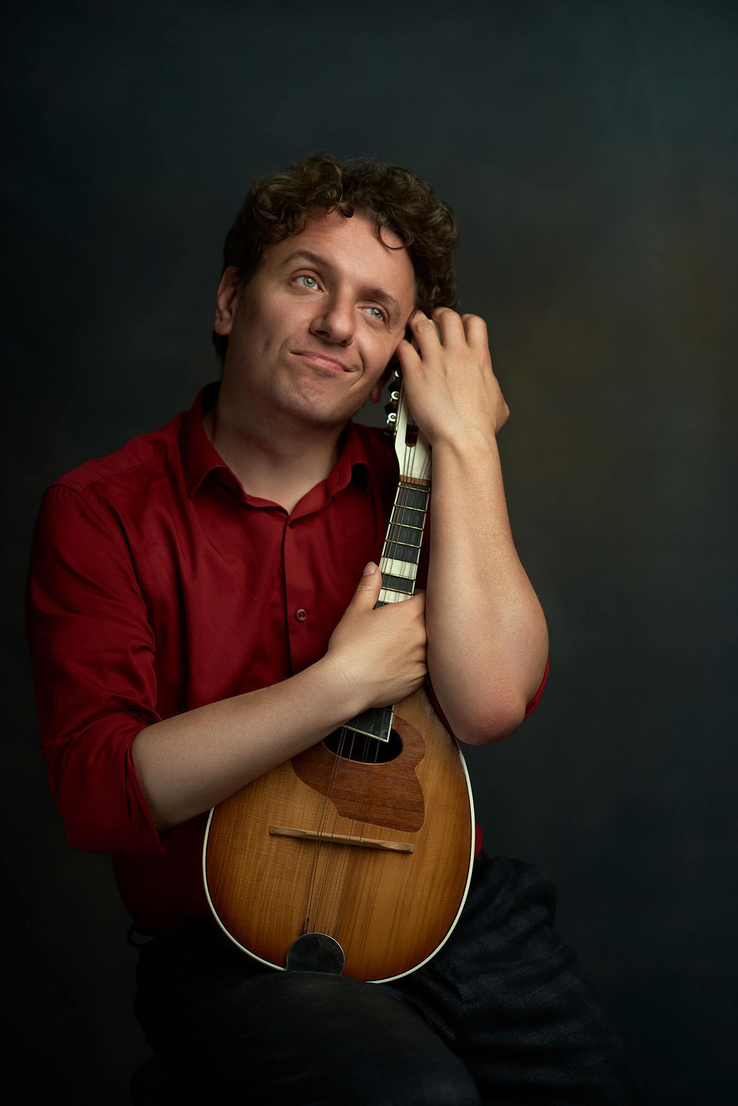 Fotografia typu personal branding - portret muzyka trzymającego mandolinę podczas sesji artystycznej autorstwa Anety Ludwig.