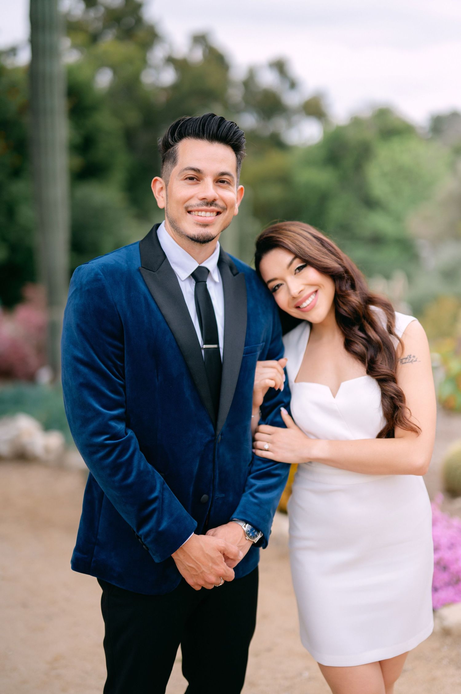 A couple in formal attire shares joyful moments together during an outdoor photoshoot.