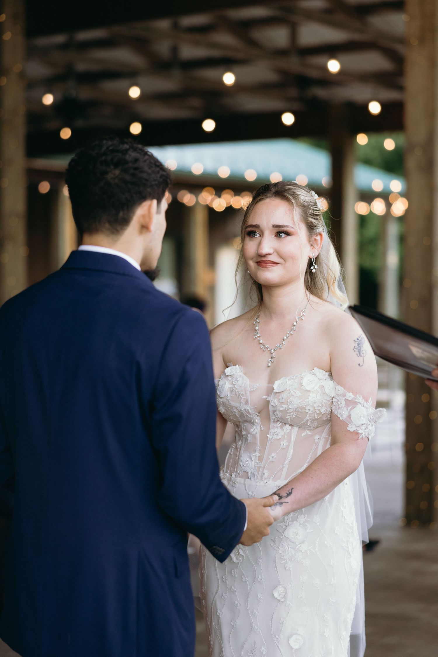 A series of wedding photos showing a bride and groom during their first look moment in an industrial venue with string lights. photographer