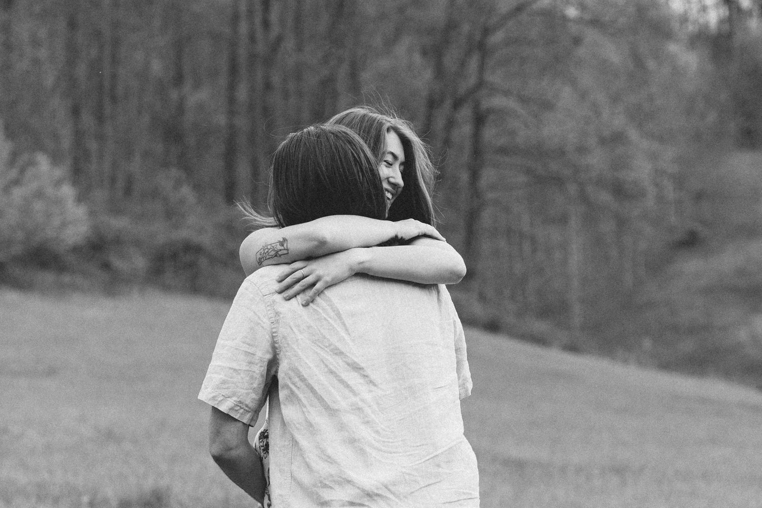 Two people embrace in an intimate moment against a wooded background. Luxury Estate Wedding Photographer in NC