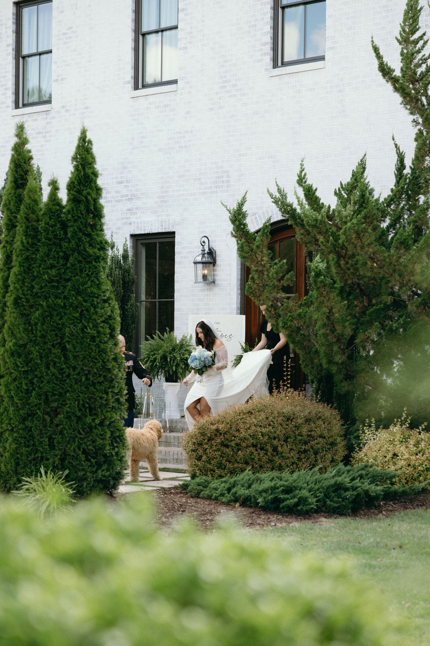 White brick building exterior with landscaped garden featuring evergreen trees. Separk Mansion Wedding Photographer