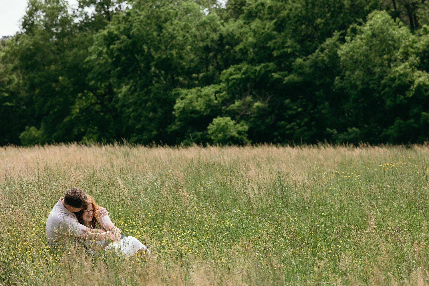 A romantic moment captured in a sunny meadow with tall grass. Twickenham House Wedding Photographer