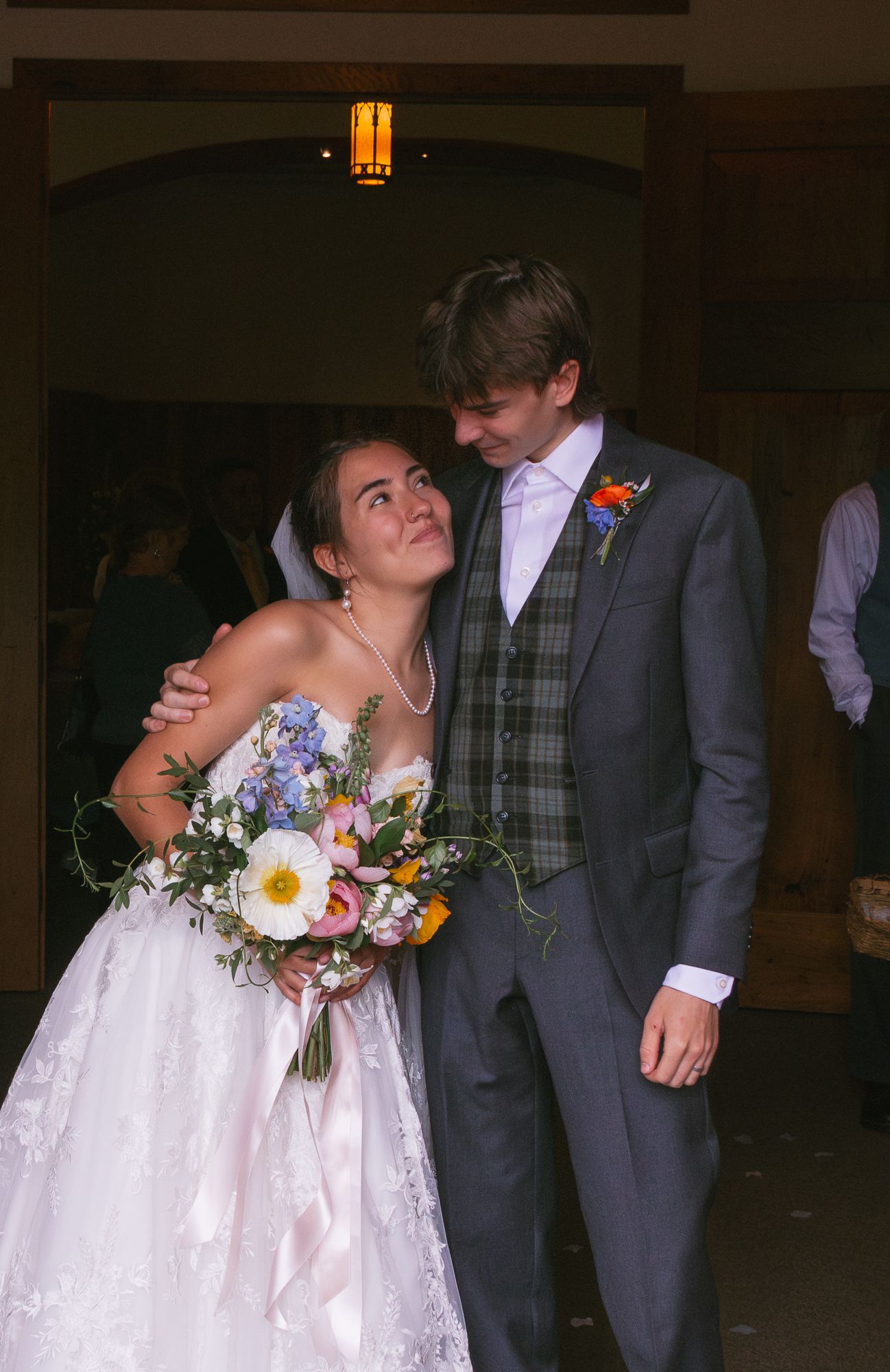 Wedding couple embracing in formal attire with bride holding colorful wildflower bouquet. Luxury wedding photographer North Carolina