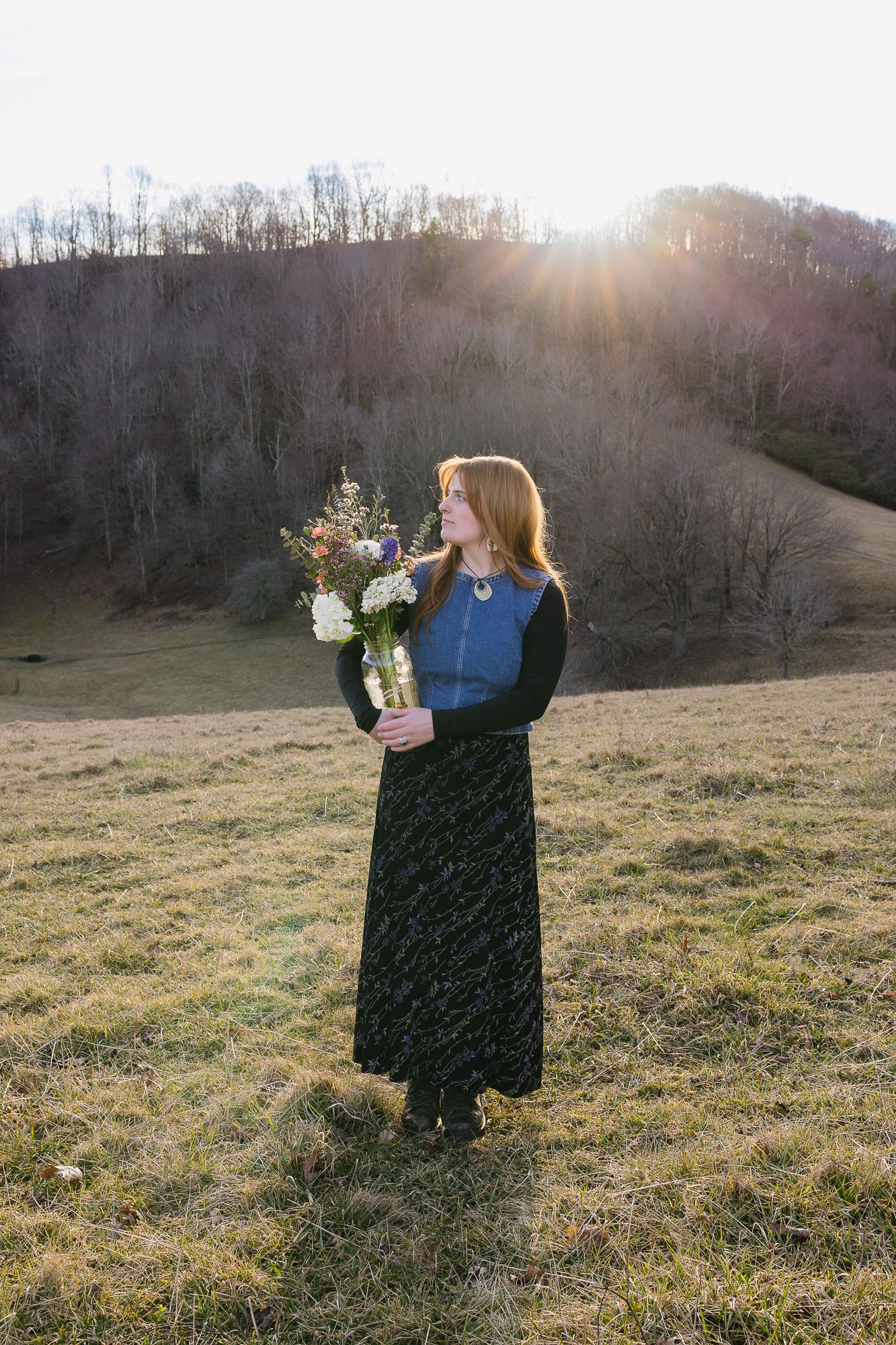 Person holding flower bouquet in sunlit field during golden hour. The Bradford, Separk  Mansion, Graylyn Estate