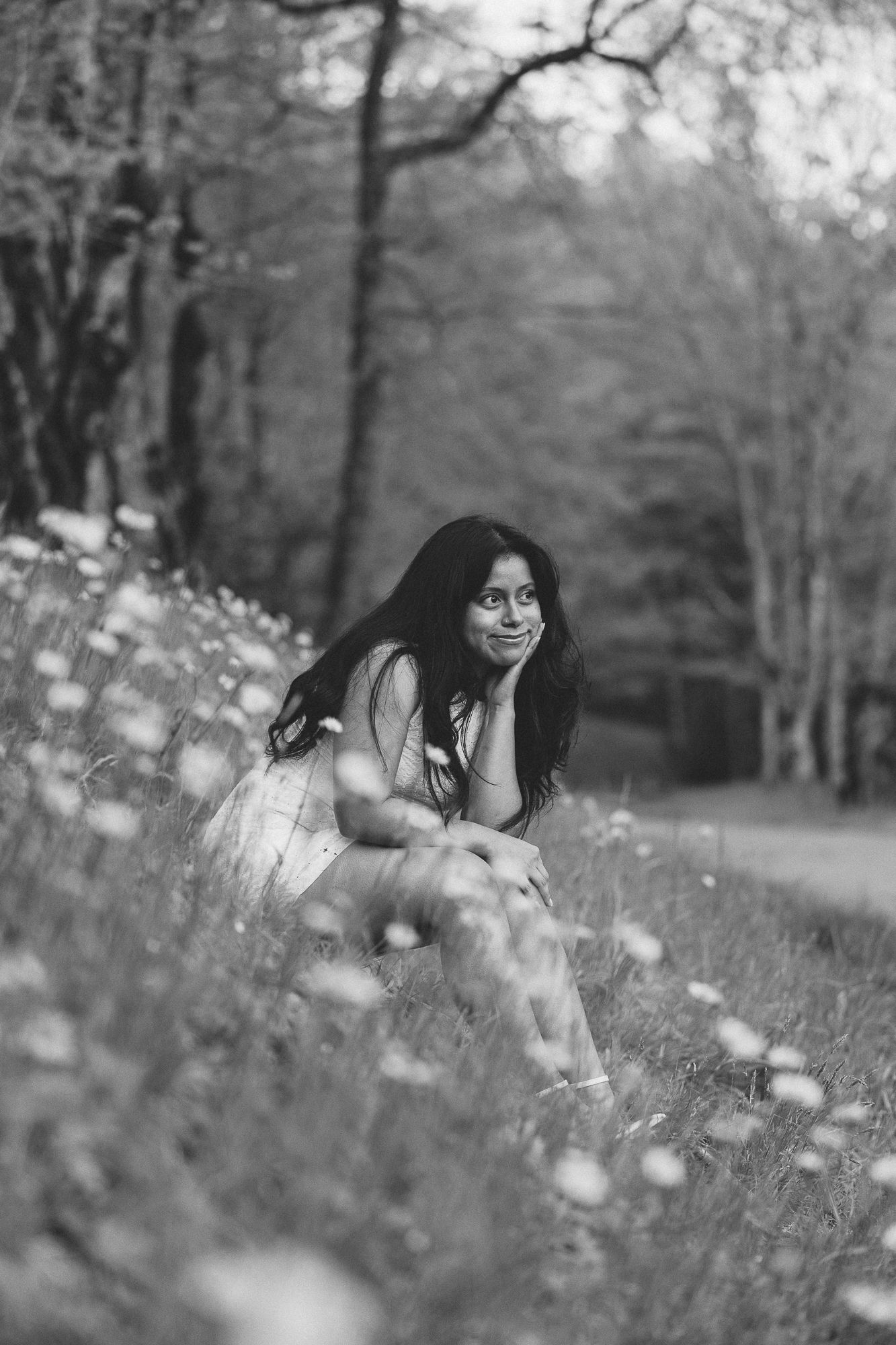 A person lies among wildflowers in a dreamy black and white portrait. Luxury Estate Wedding Photographer in NC