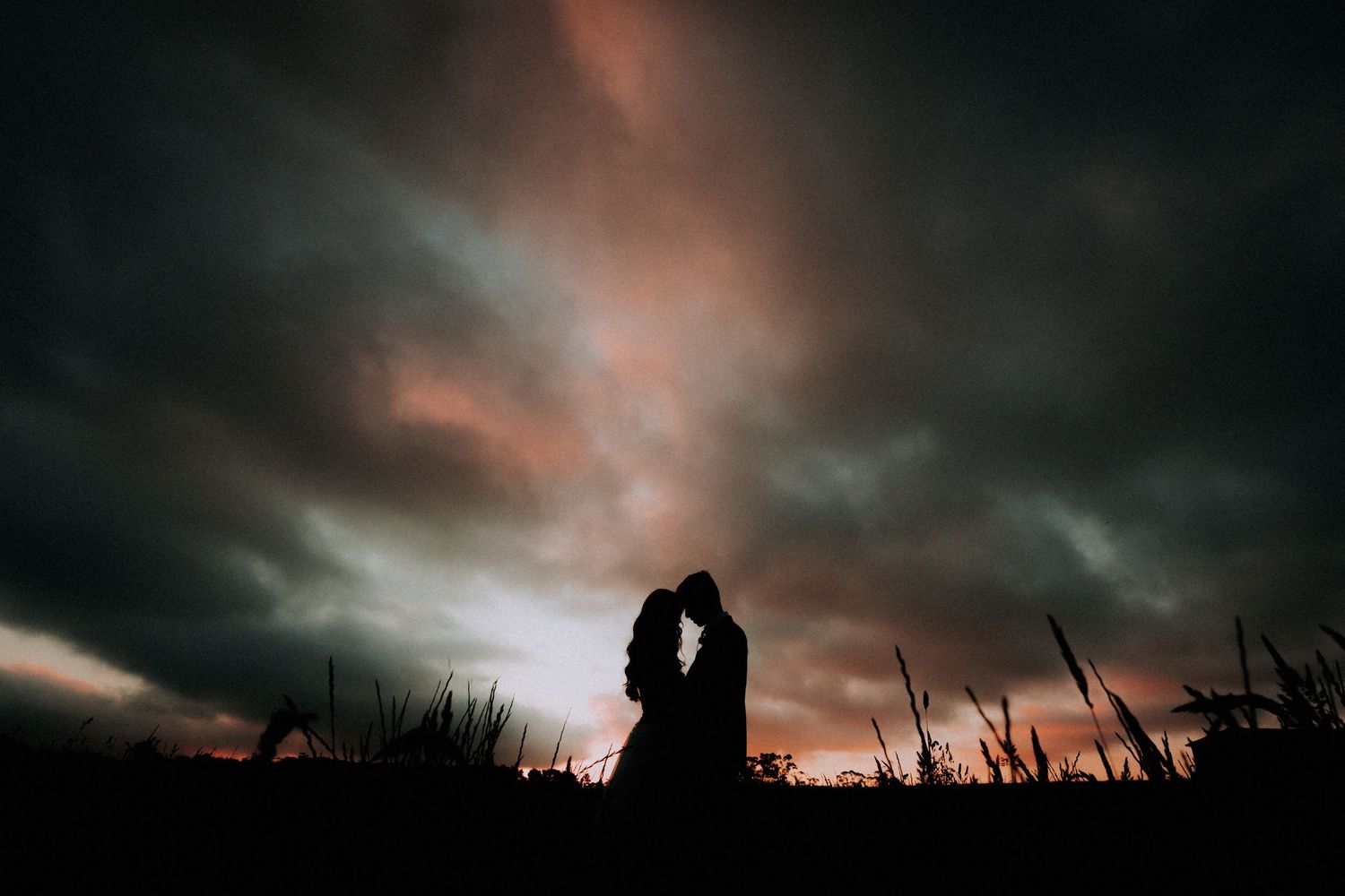 Dramatic silhouettes against a moody sunset sky with dark clouds.
