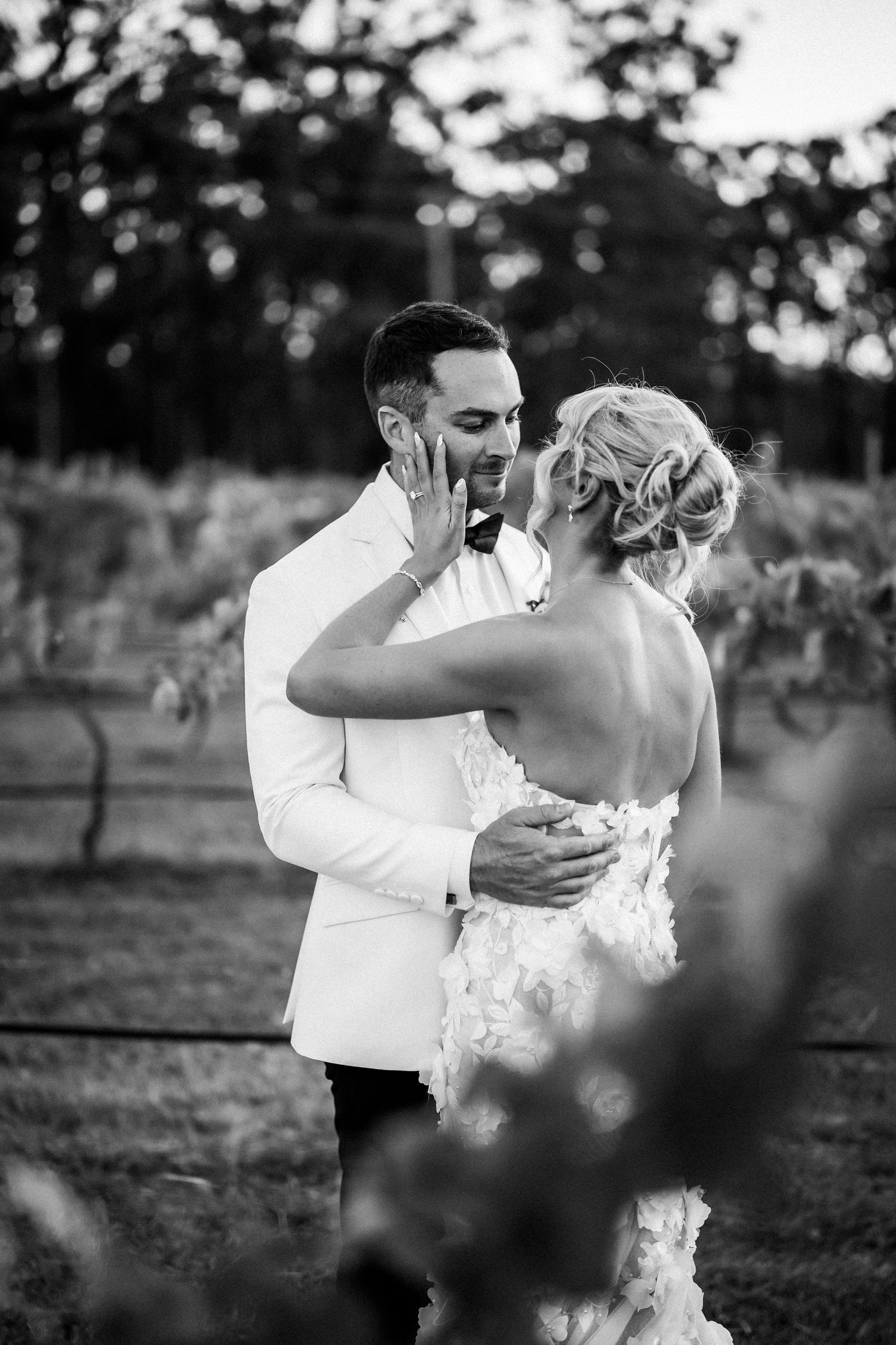 Black and white wedding photography capturing tender moments between newlyweds in a garden setting.