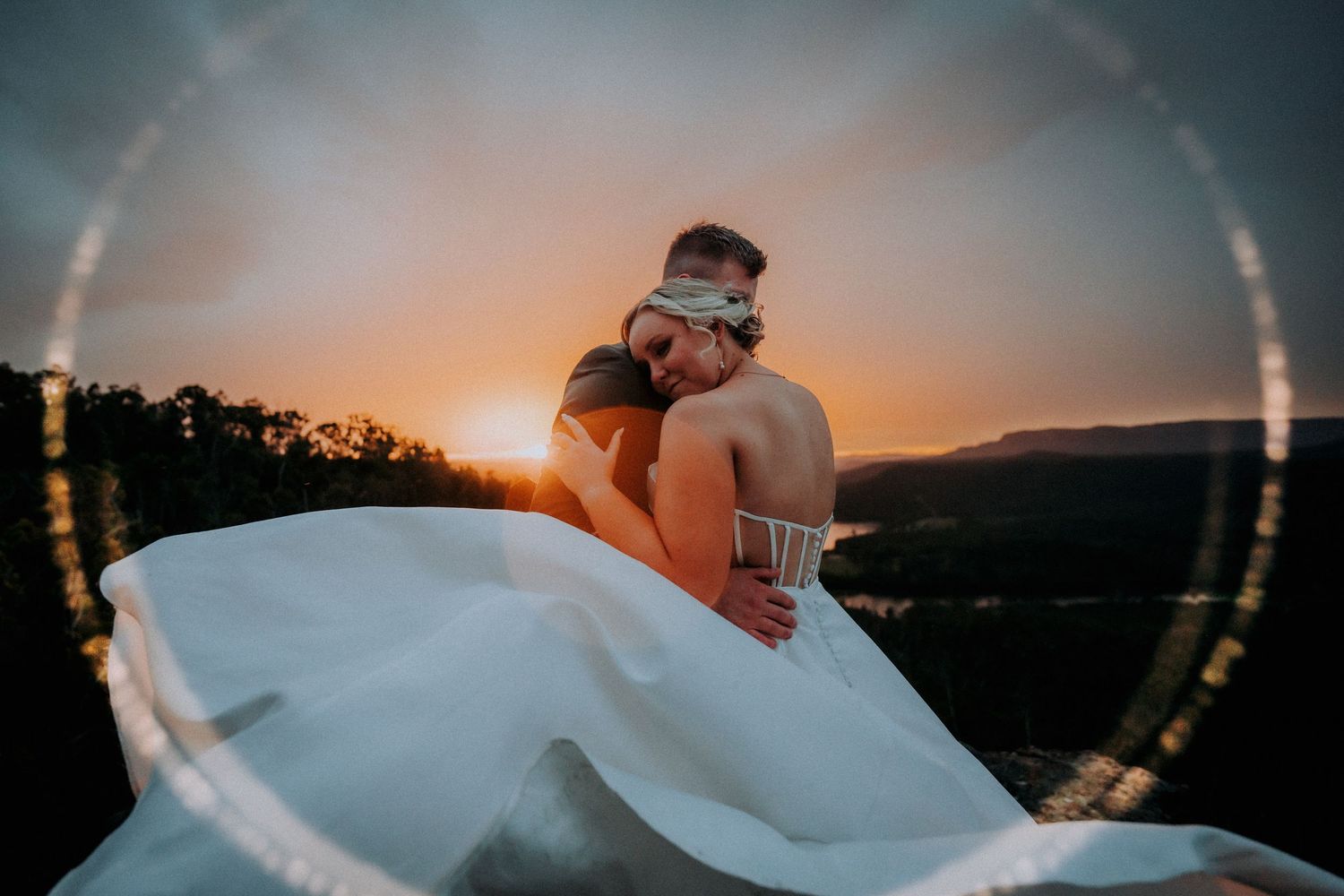 Artistic wedding photography with lens flare effect during golden hour.