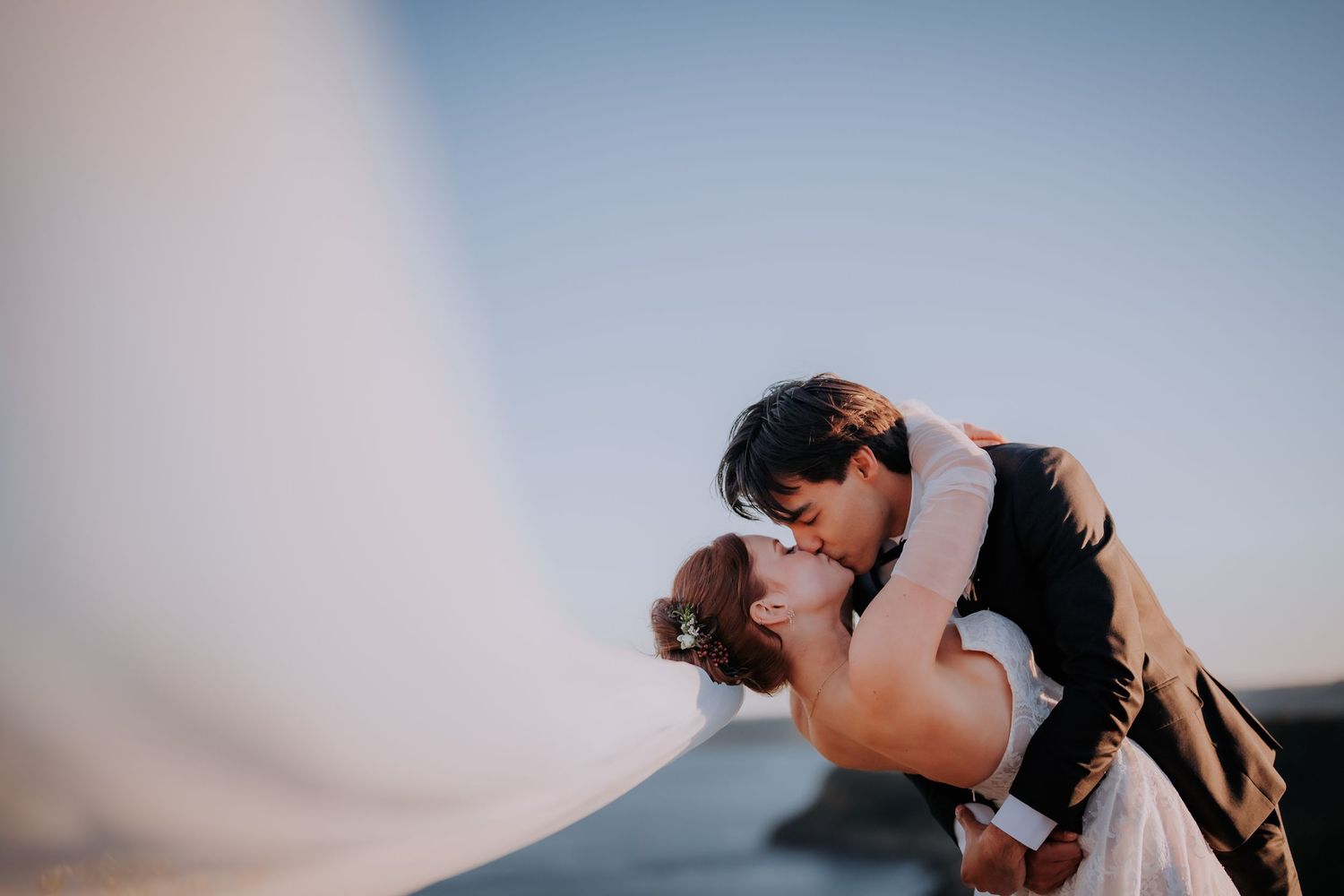 Romantic wedding couple sharing intimate moments at sunset in a scenic outdoor setting.