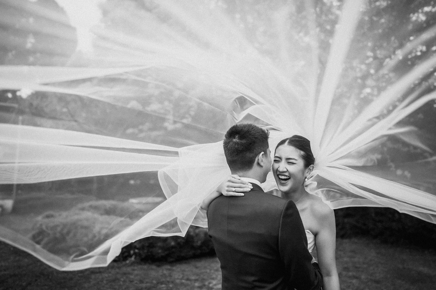 Joyful wedding moment captured with flowing veil creating dramatic effect.