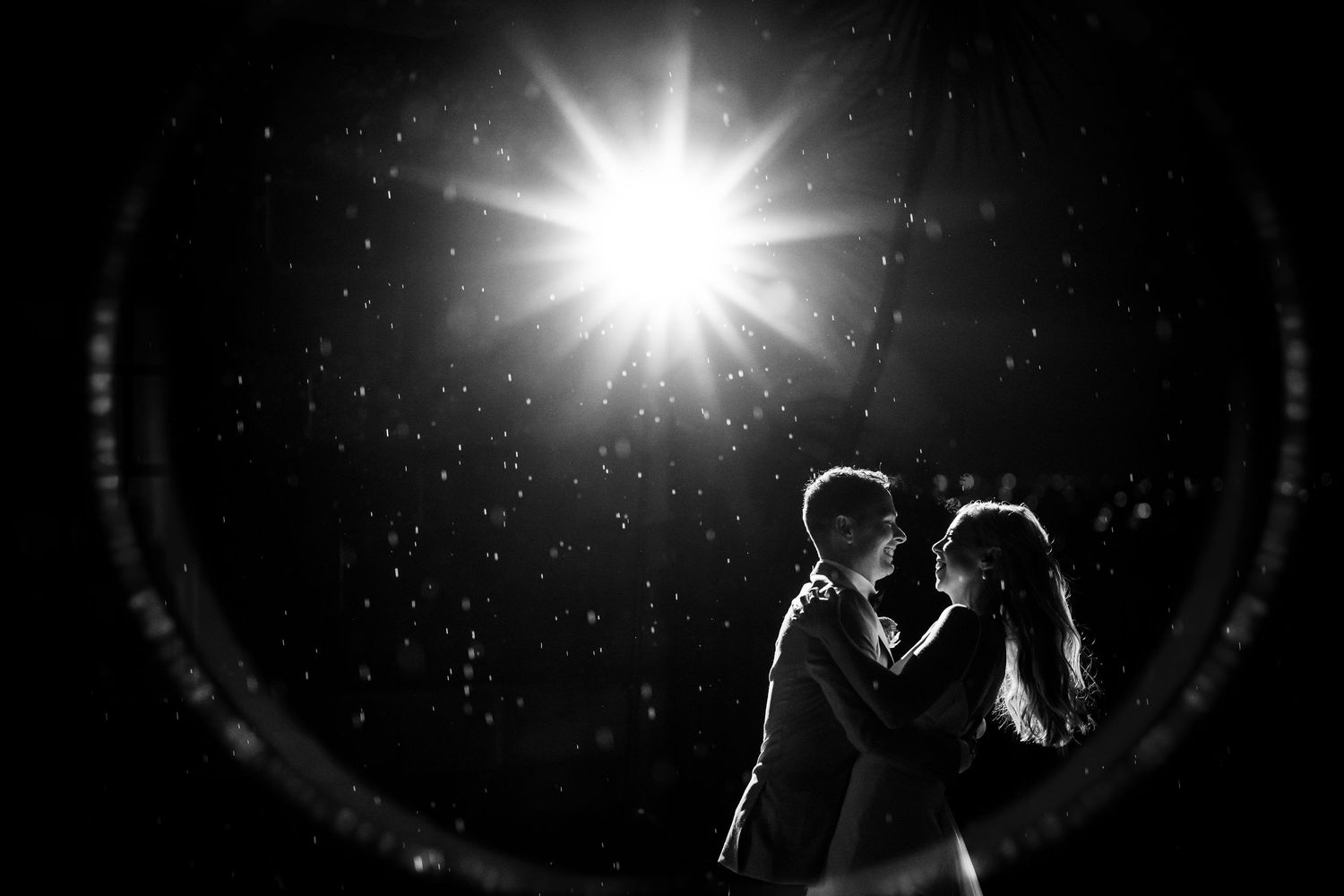Dramatic silhouette of couple with sunburst effect creating romantic wedding atmosphere.