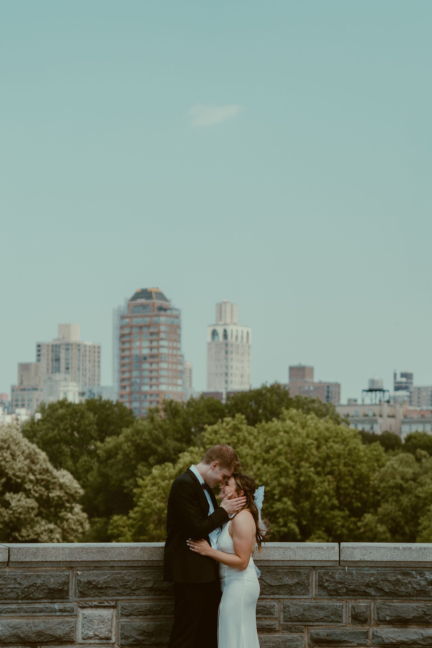 A romantic city skyline scene with the New York City skyline and lush green trees in the background.