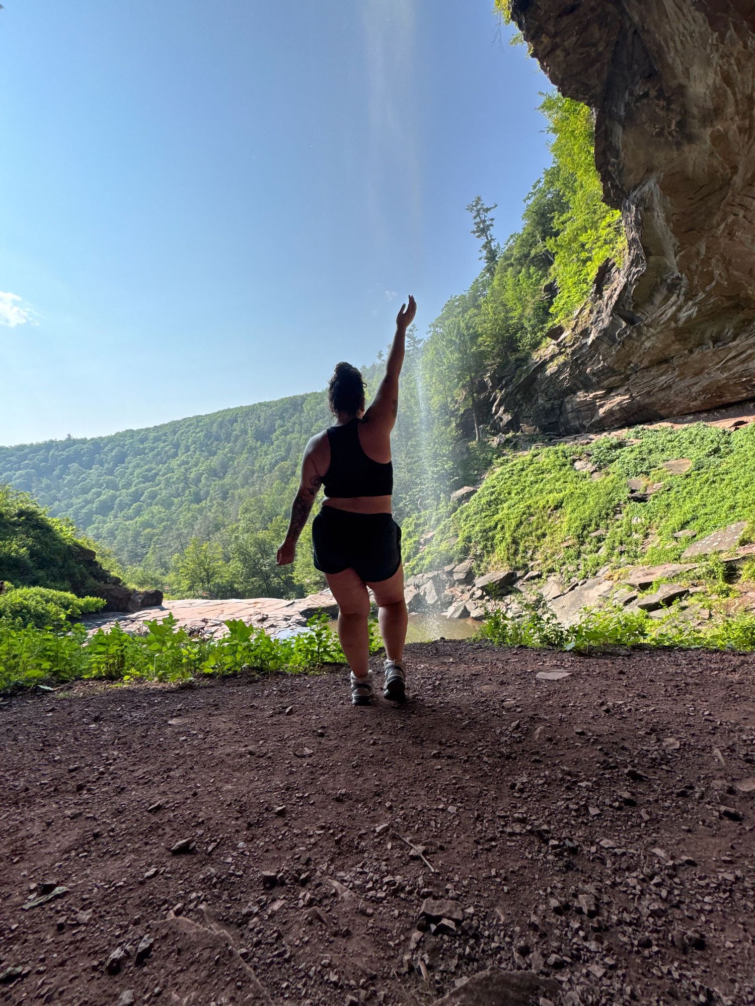 A hiker admires the natural view through multiple cave arches along a scenic mountain trail.