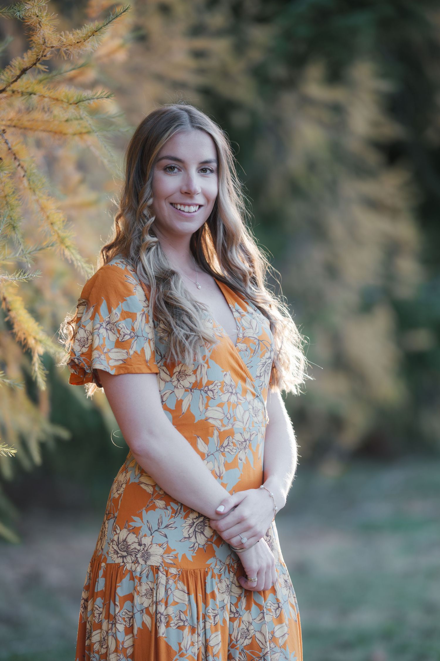 stunning bride posing in in late autumn in an orange dress with golden sunset light in rural setting