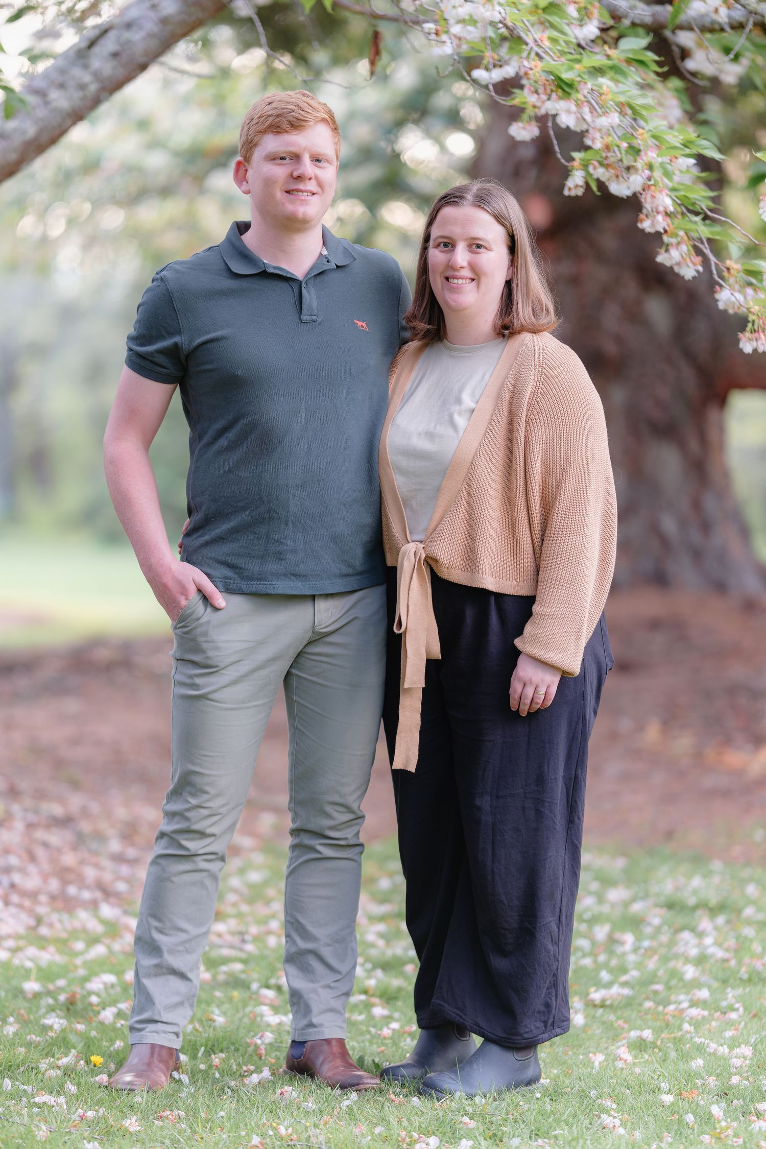 Couple posing together in a garden with white wildflowers blooming around them.