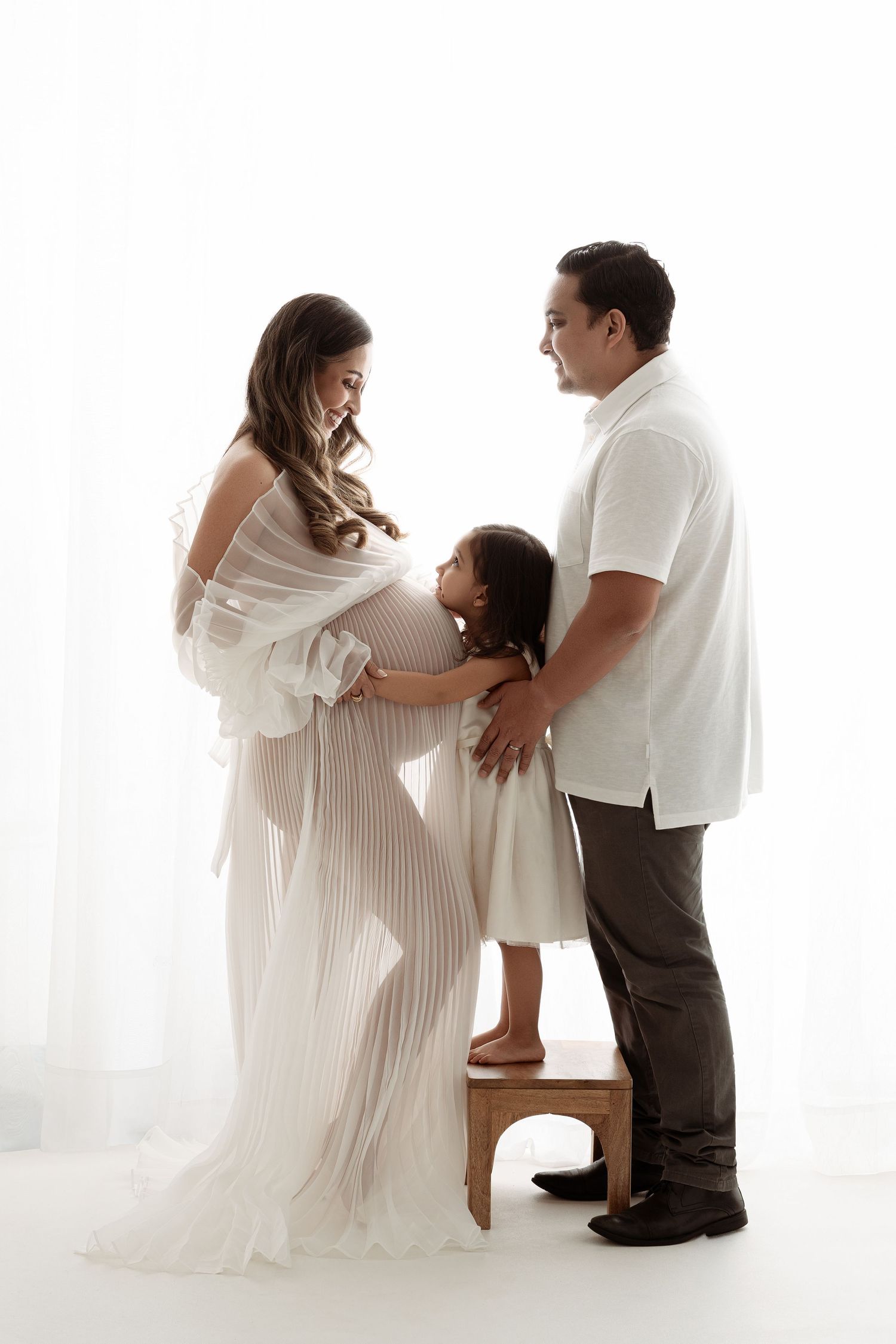 Three connected images showing tender family moments in white studio setting with soft lighting and ethereal atmosphere. Paloma Schell