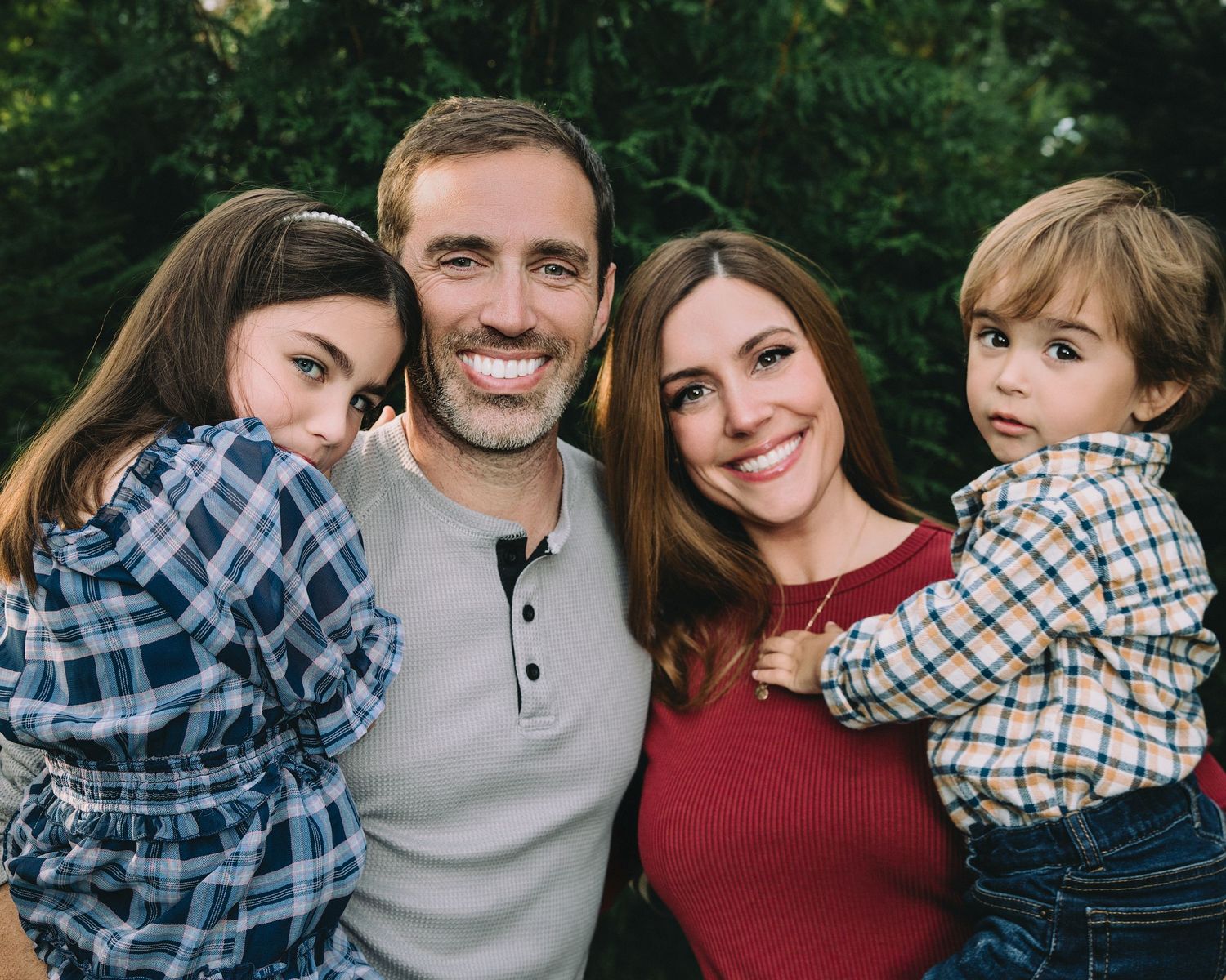 family of 4 hugging each other while the daughter displays shyness