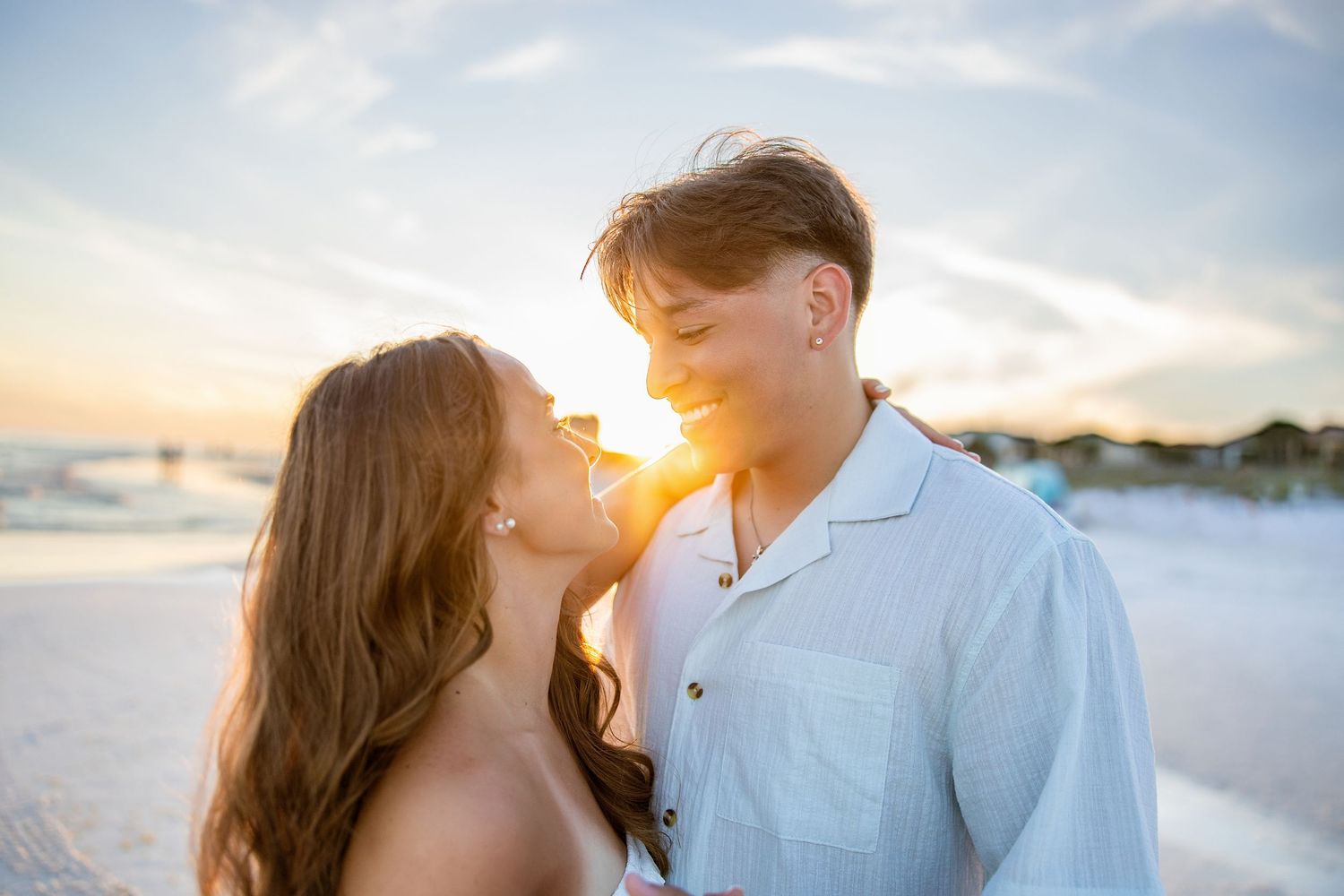 Romantic couple nearly kissing on a beach with a stunning golden sunset behind them.