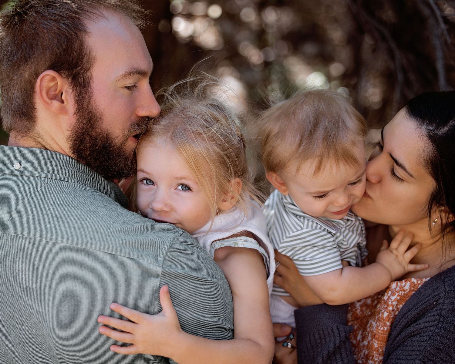 family of for embracing each other while kids are being kissed by their parents