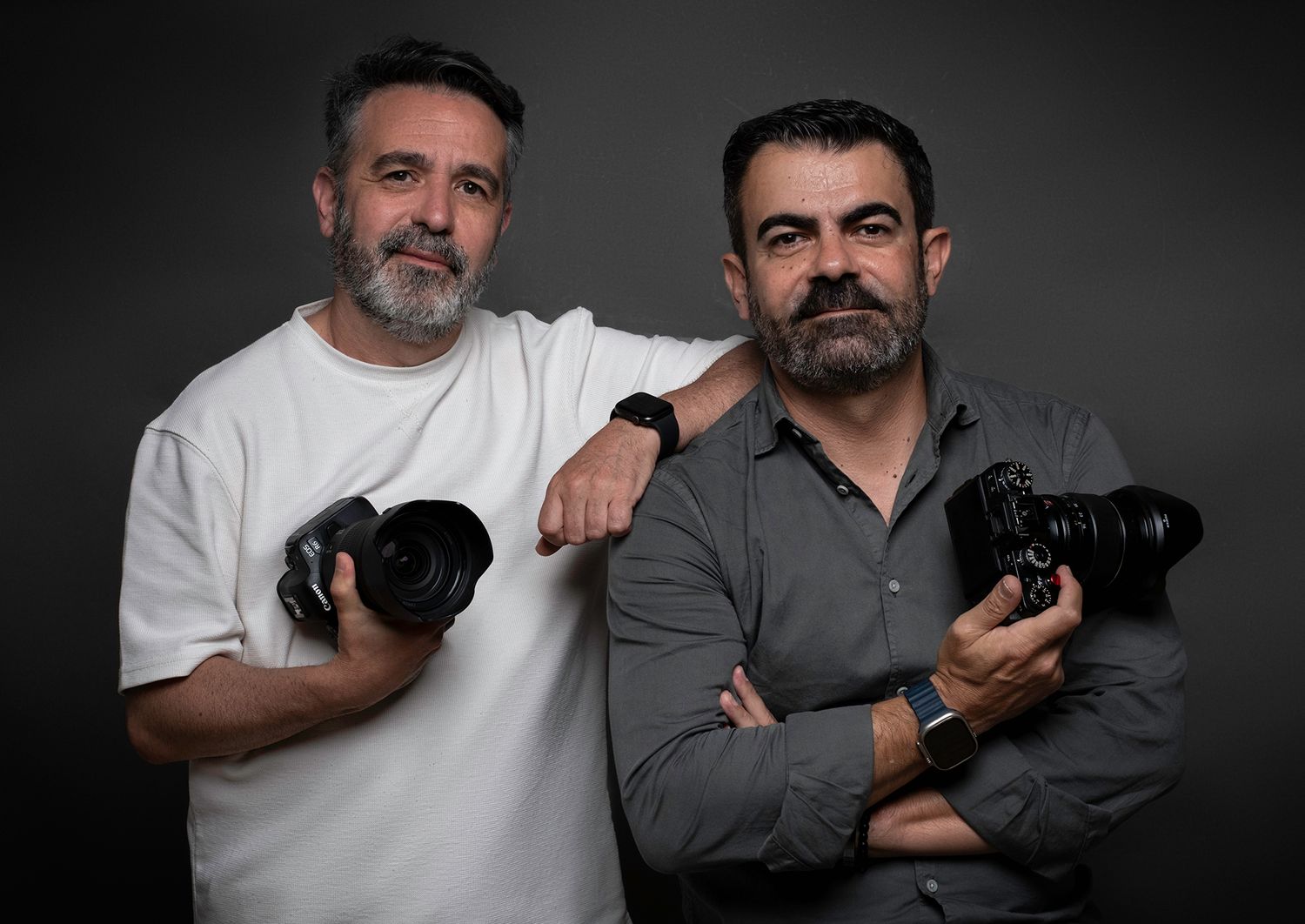 Professional photographers holding cameras while posing for studio portrait.