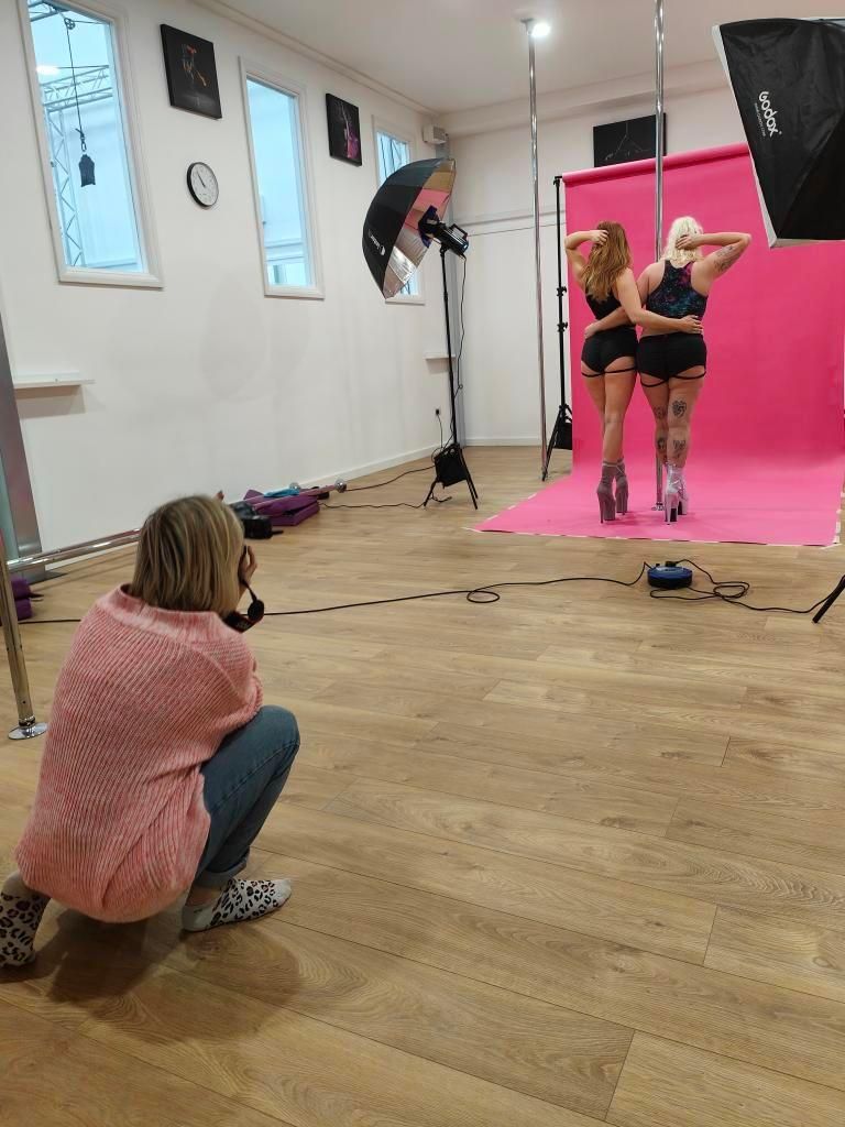 Photography session in progress with professional lighting setup against pink backdrop.