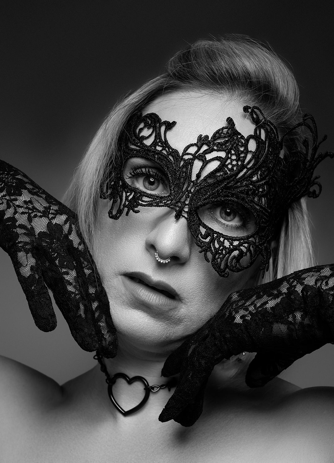 Monochrome portrait with black lace mask and matching gloves.
