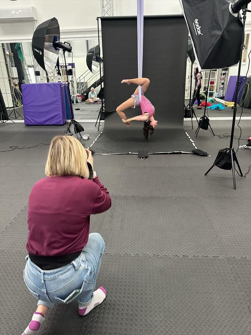 Studio photography session capturing aerial dance performance against black backdrop.