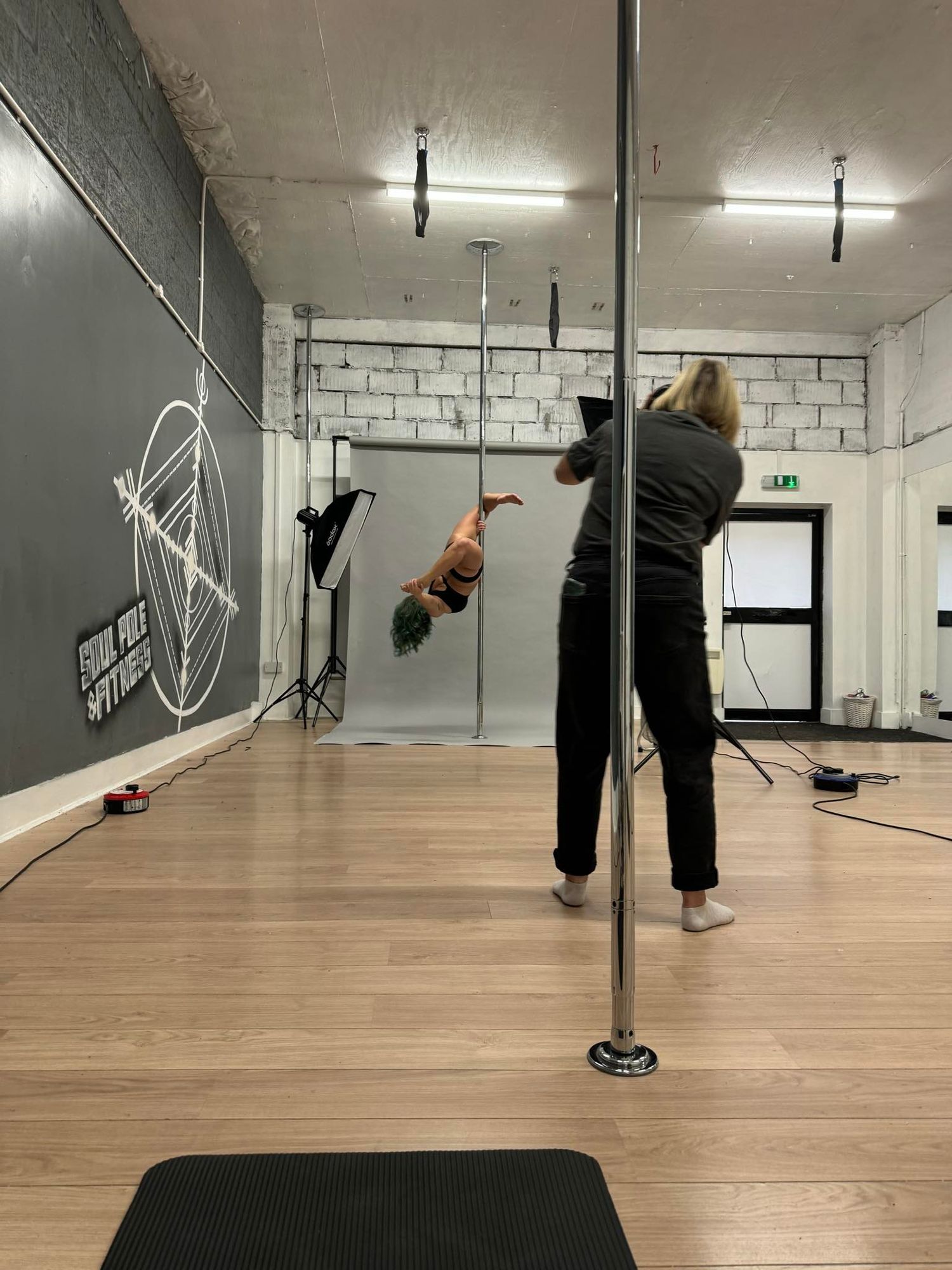 Dance studio interior with pole equipment and practice session in progress.