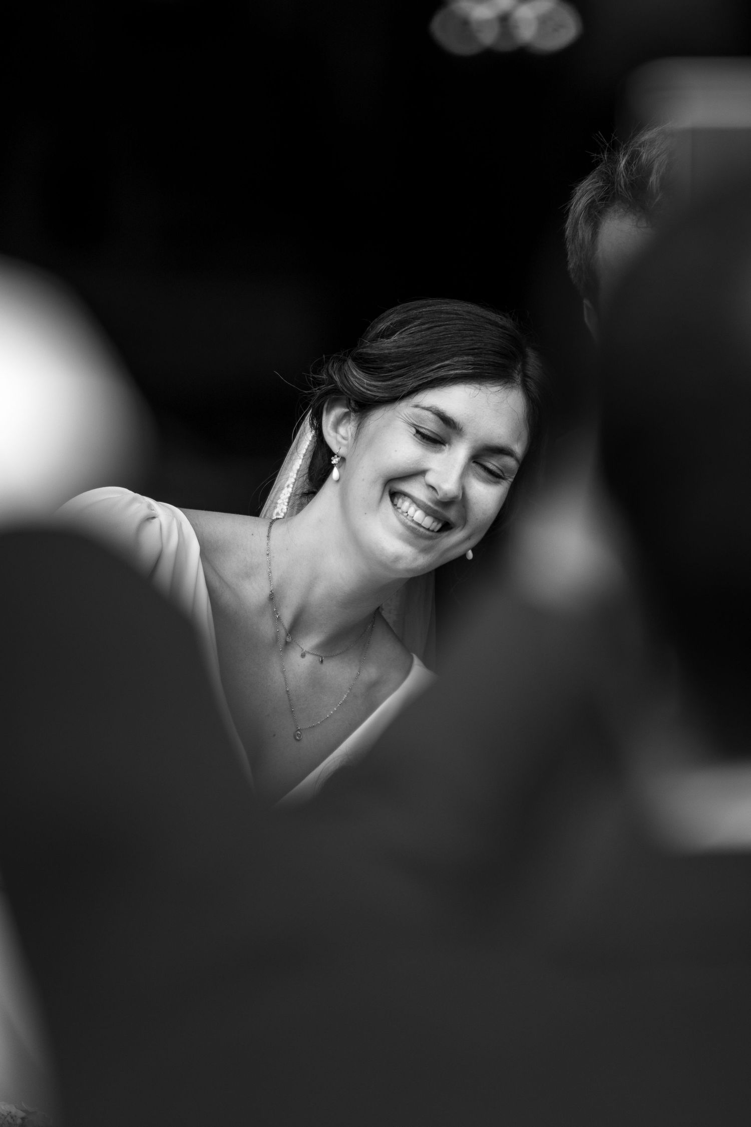 Black and white portrait of a radiant bride laughing with eyes closed during wedding ceremony.