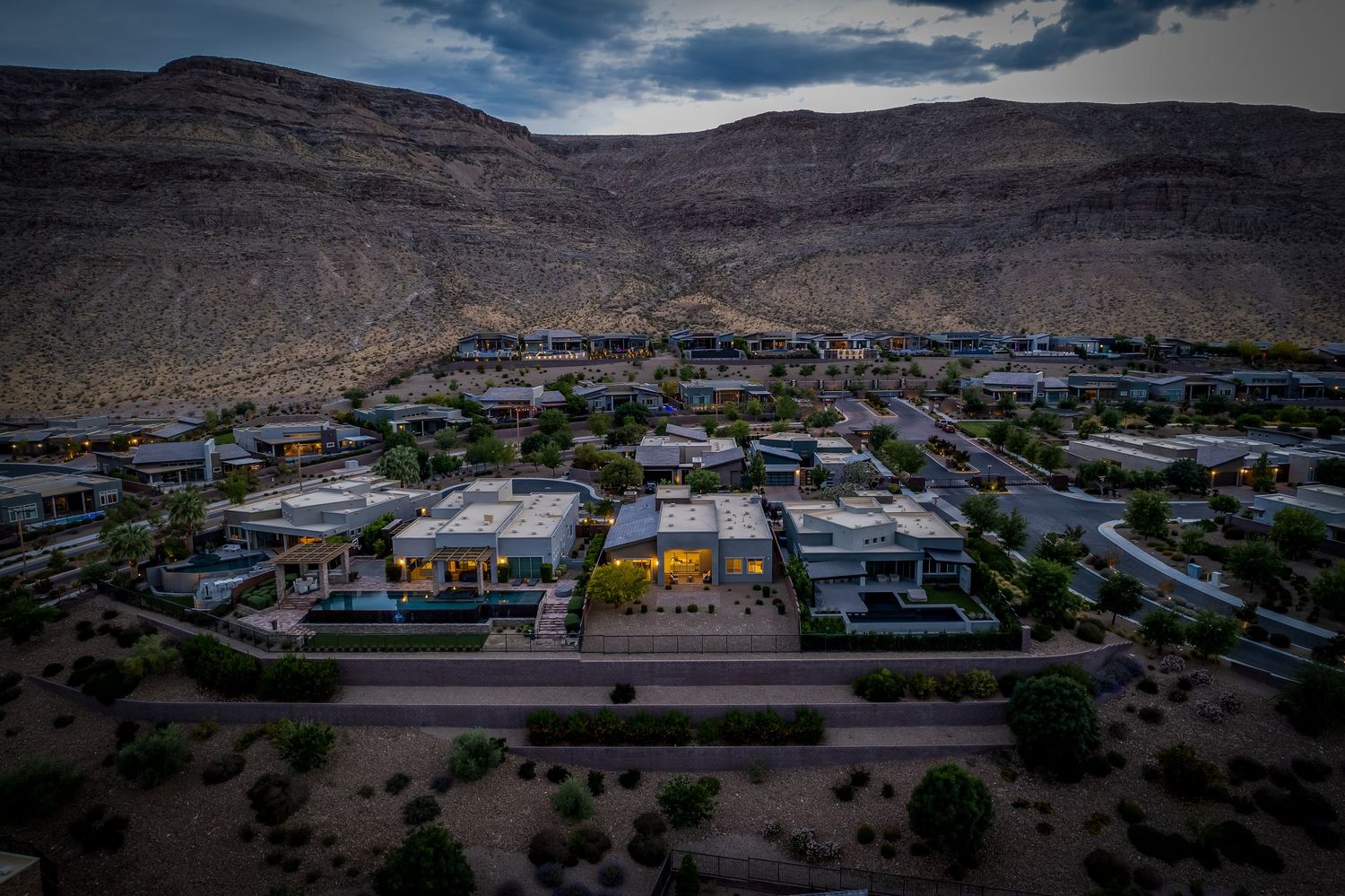 Desert mountain landscape with residential development nestled among rugged terrain at dusk.