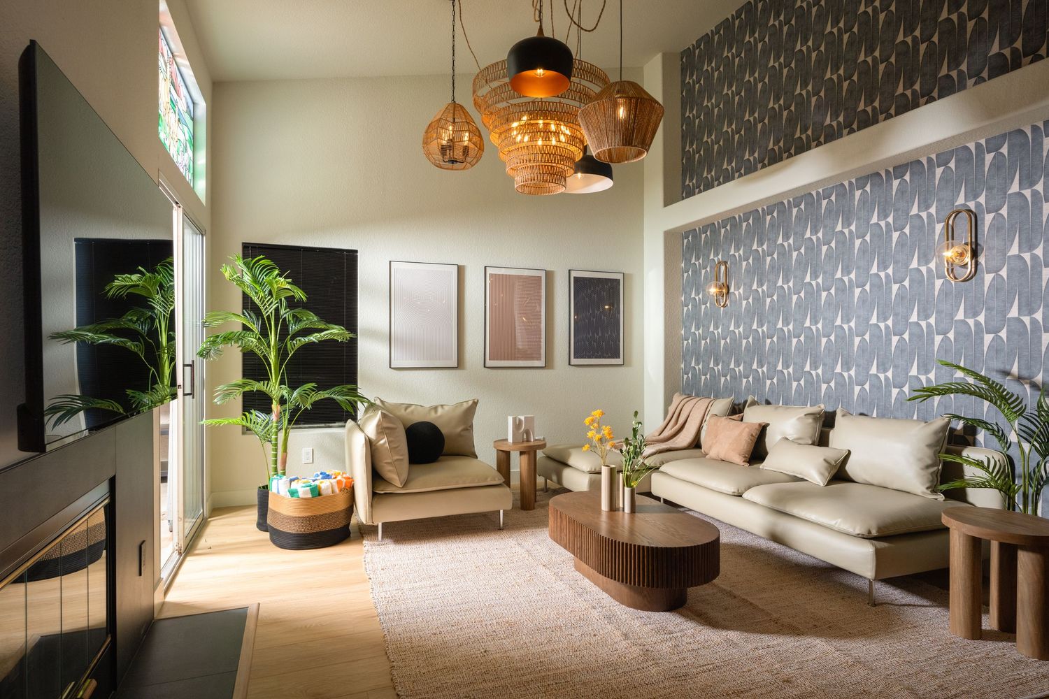 Modern living room with pendant lights, neutral sofa, wood coffee table, tropical plant, and patterned wallpaper accent wall.