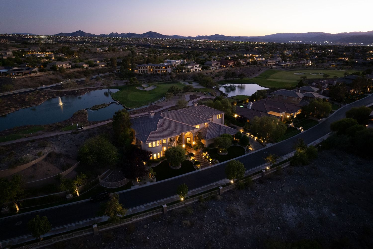 Panoramic aerial view of a residential neighborhood at dusk with city lights beginning to illuminate the landscape.
