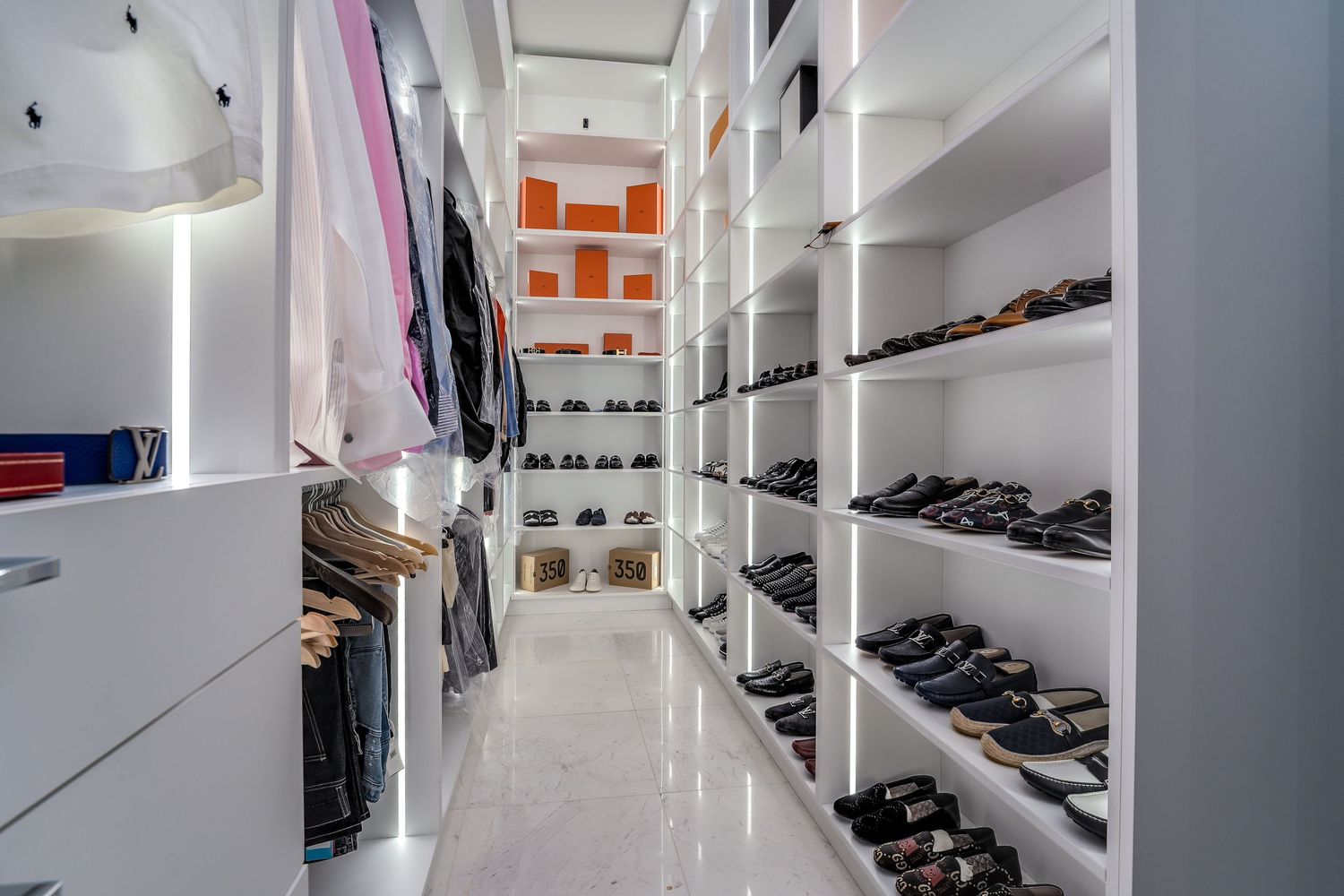 Spacious walk-in closet with white shelving and organized storage for clothes and shoes.