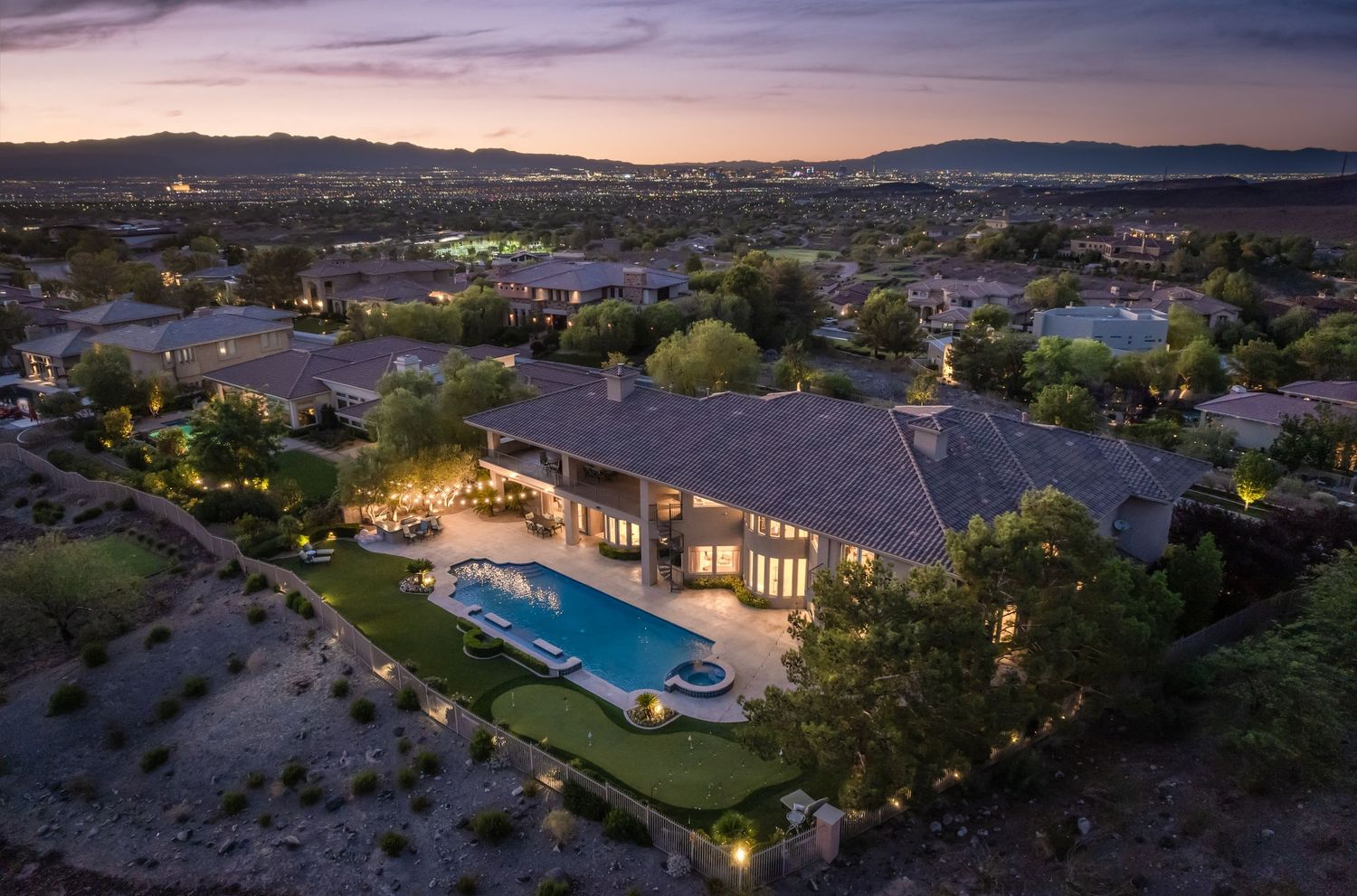 Aerial view of luxury residential community with swimming pool and desert landscape at sunset.