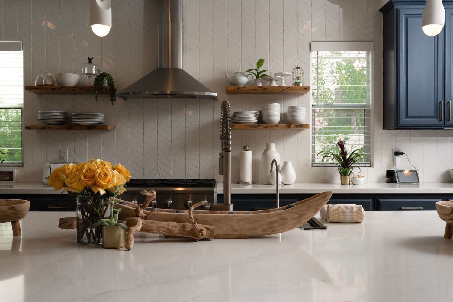 Bright modern kitchen with white countertops, wooden accents, and natural light streaming through windows.
