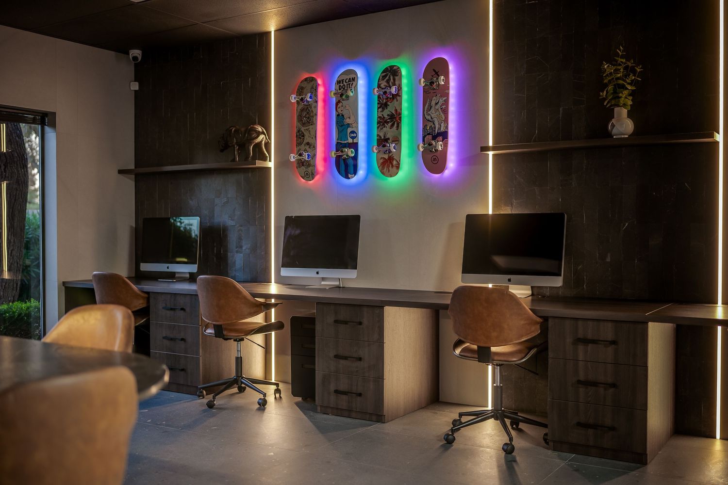 Modern game room with ambient lighting and colorful LED skateboard wall display.