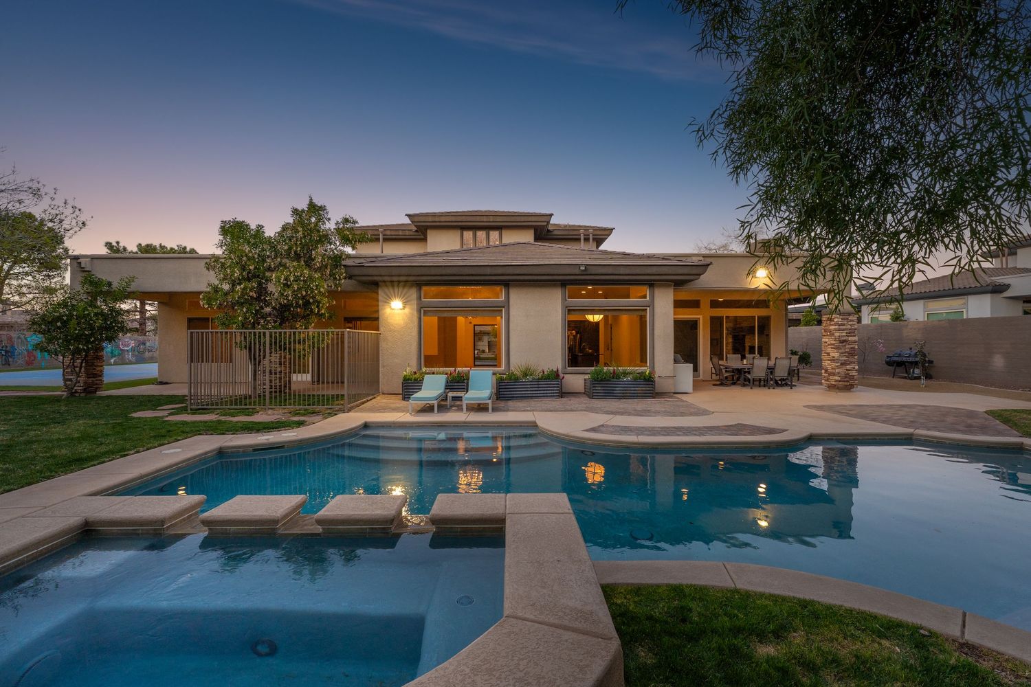 Luxury backyard oasis featuring a geometric pool design and modern architecture at twilight.