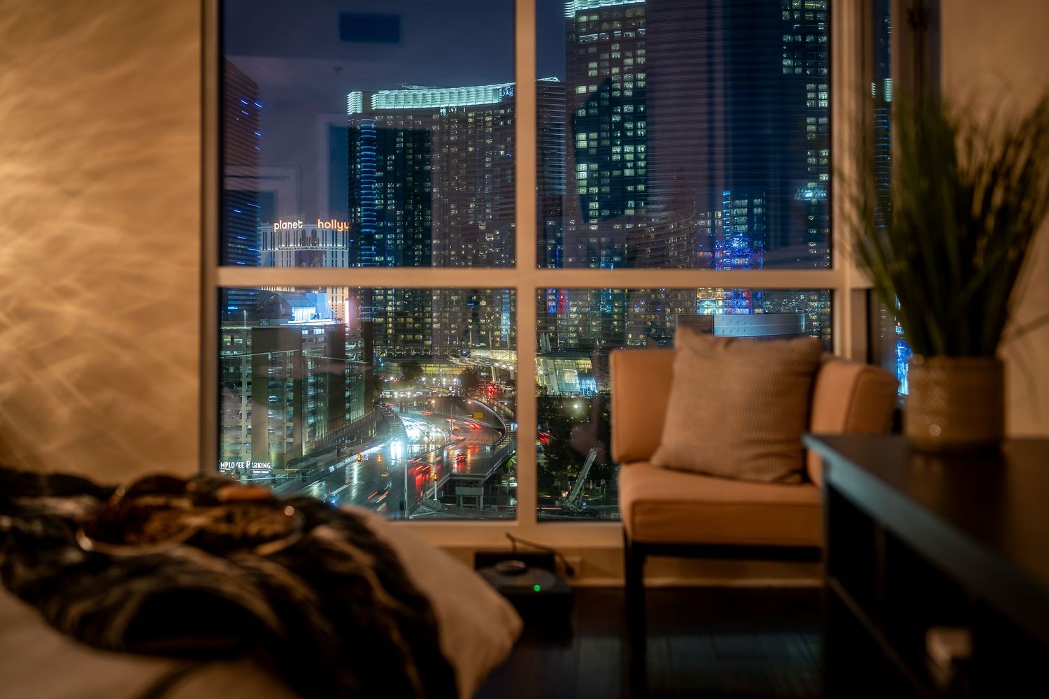 Modern luxury apartment interior with city skyline views at night through floor-to-ceiling windows.