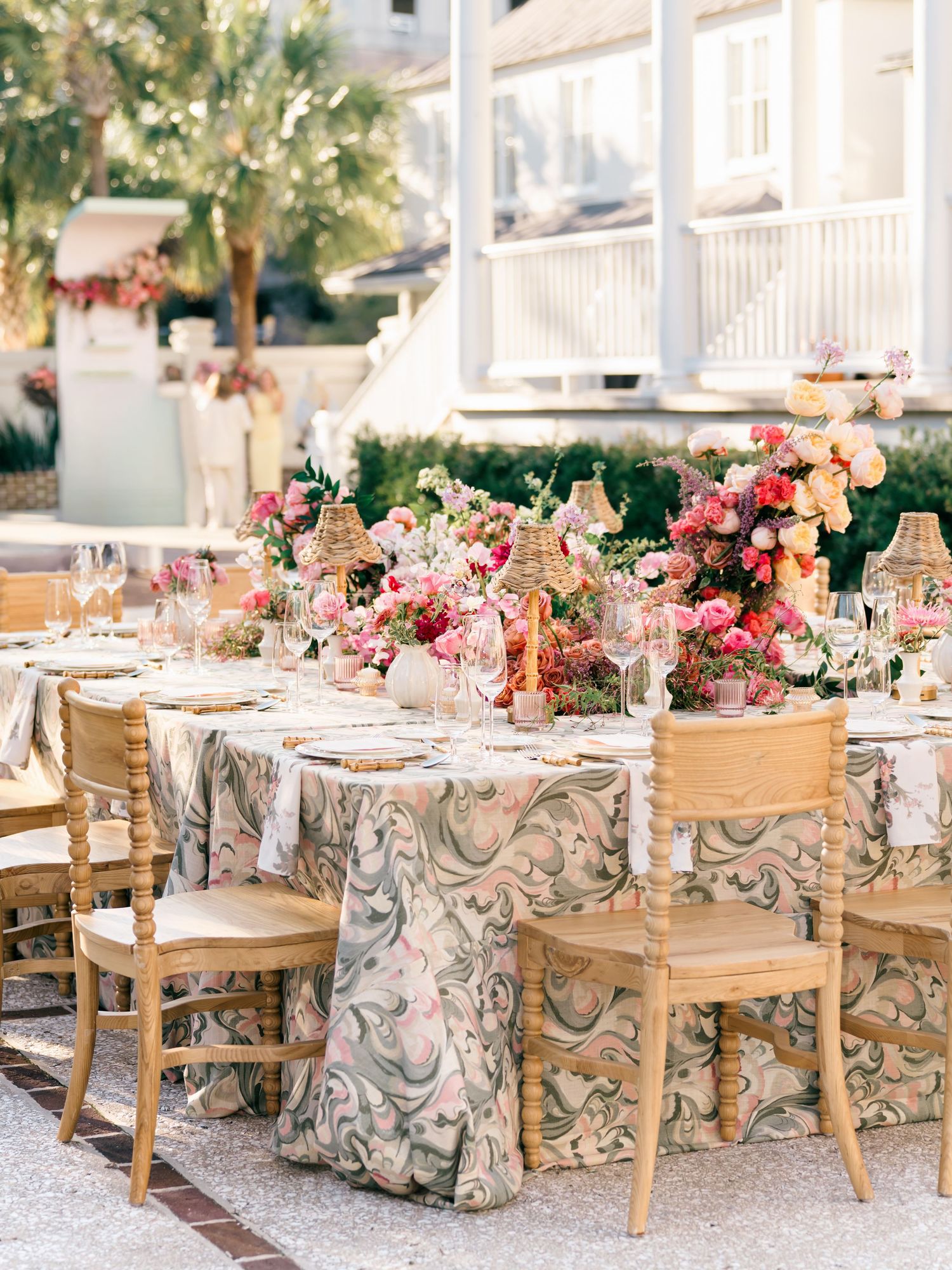 Elegant outdoor wedding reception tables decorated with floral arrangements and wooden chairs.